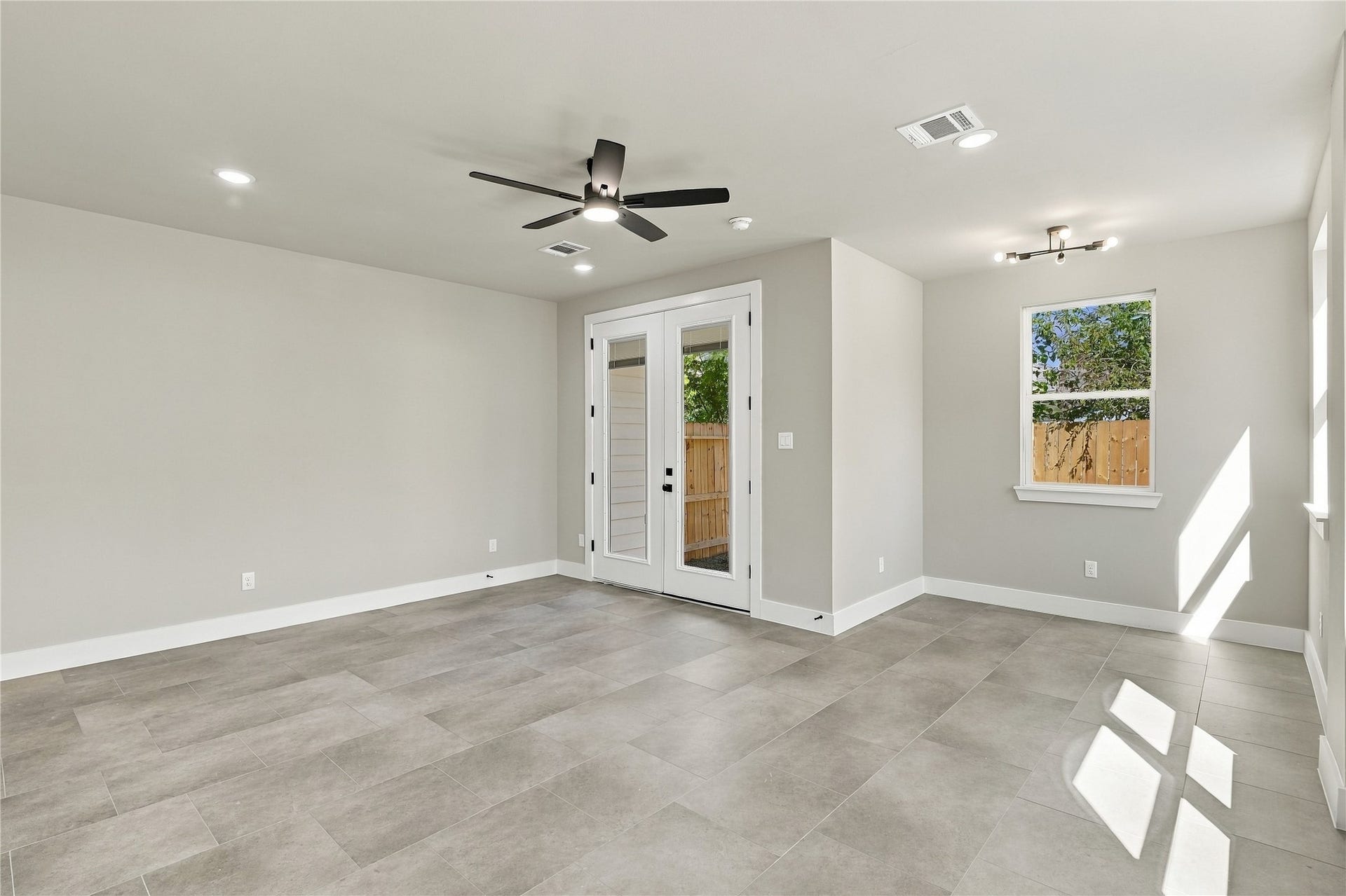 4313 Clover Street, #A/B, Houston, TX 77051 Spacious and bright room with sleek tile flooring, modern light fixtures, and French doors leading outside.