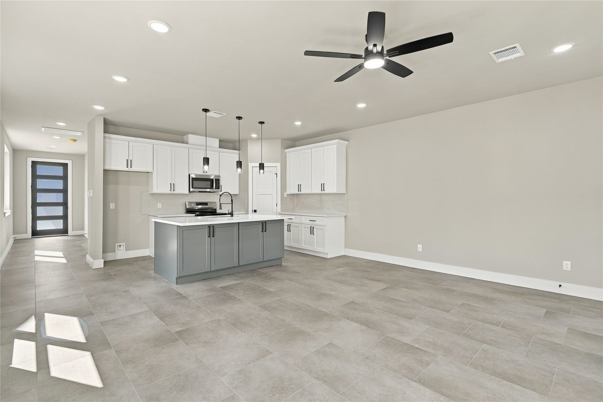4313 Clover Street, #A/B, Houston, TX 77051 Modern open-concept living area featuring a sleek kitchen with a central island, stylish cabinetry, and stainless steel appliances, complemented by elegant tile flooring and ample natural light.