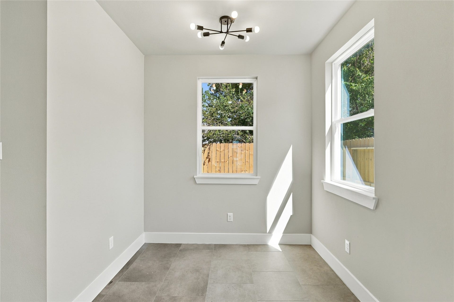 4313 Clover Street, #A/B, Houston, TX 77051 Bright and inviting room with modern lighting, neutral walls, and large windows overlooking a lush backyard, perfect for a cozy dining area or office space.