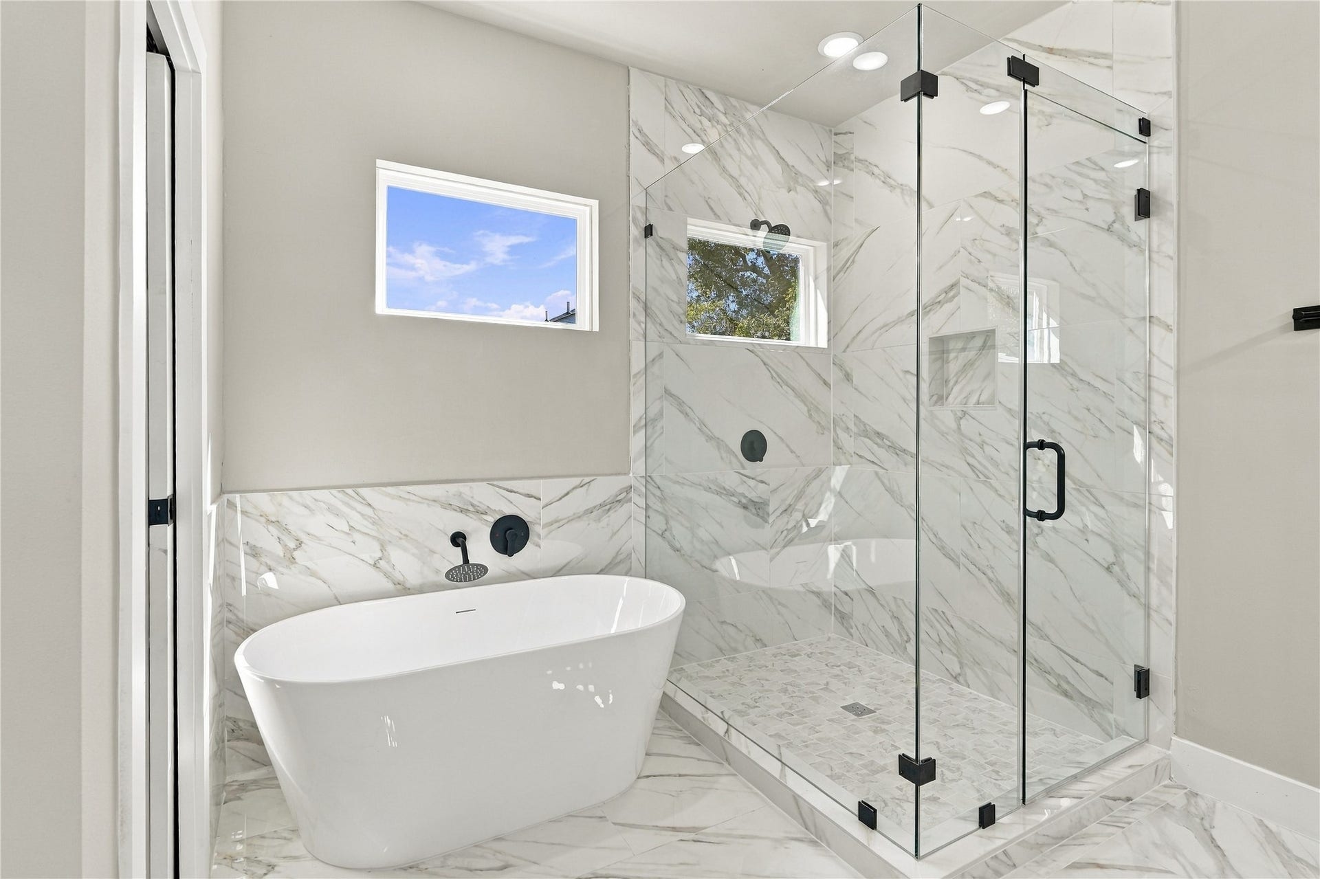 4313 Clover Street, #A/B, Houston, TX 77051 Luxurious bathroom featuring a sleek, freestanding bathtub and a spacious glass-enclosed shower, all set against elegant marble walls and flooring.