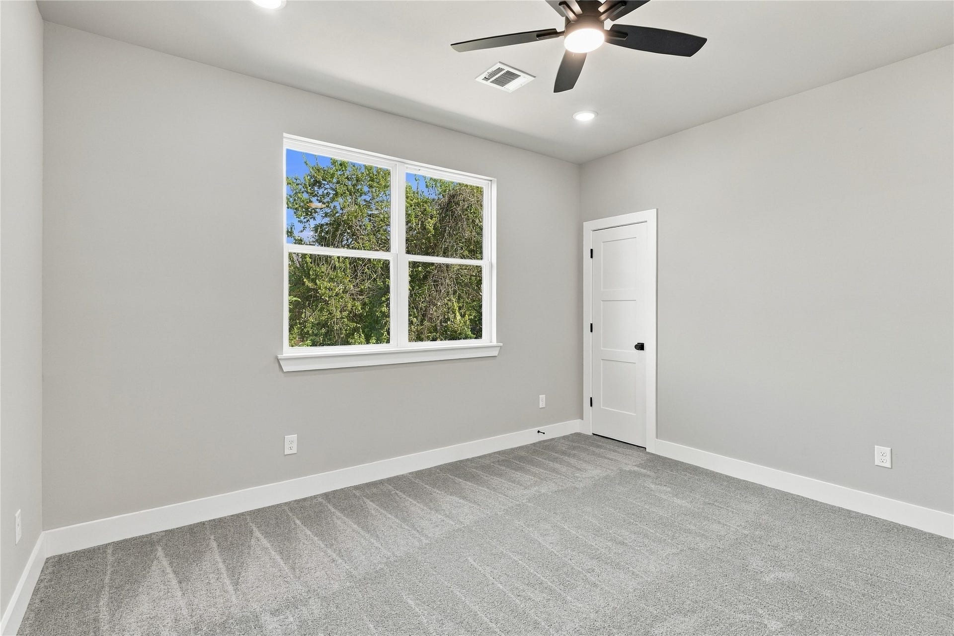 4313 Clover Street, #A/B, Houston, TX 77051 Bright and spacious bedroom featuring large windows, soft gray walls, plush carpeting, and a modern ceiling fan for comfort.