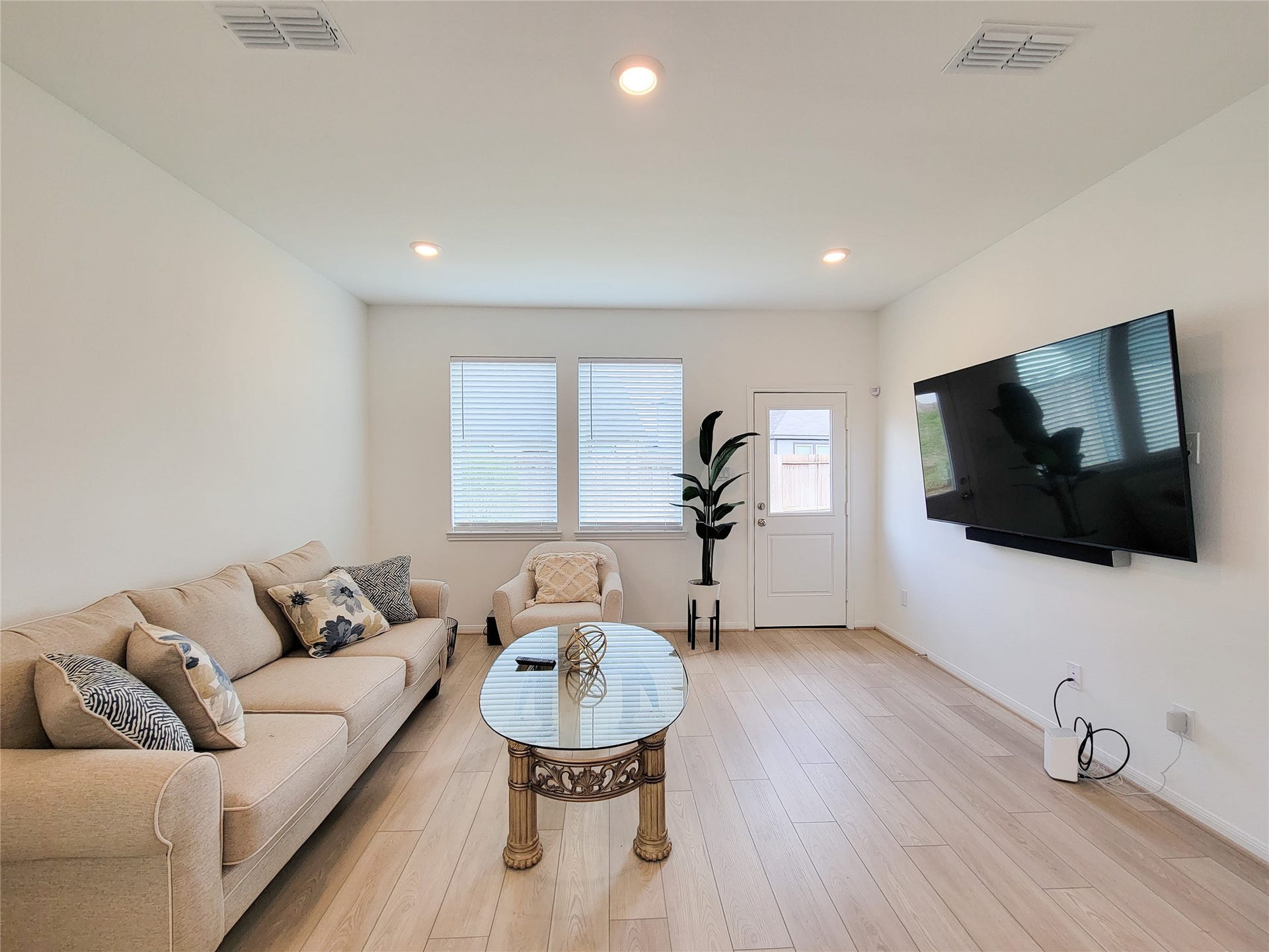2719 Forest Retreat Lane, Missouri City, TX 77489 Bright and modern living room with light wood flooring, neutral walls, and recessed lighting.