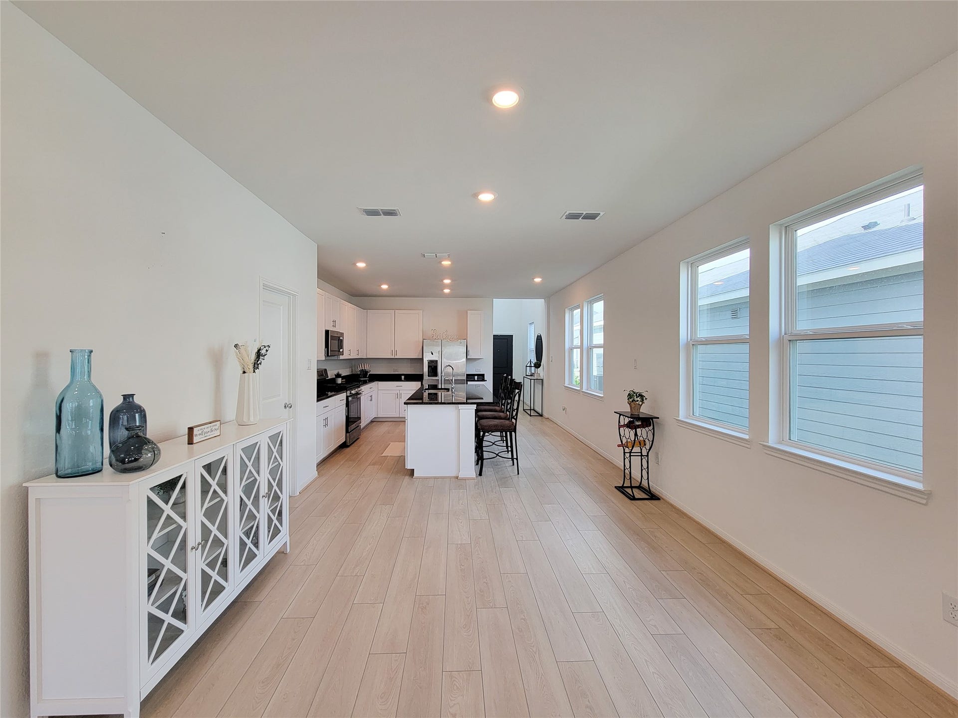 2719 Forest Retreat Lane, Missouri City, TX 77489 Spacious, open-concept kitchen and dining area with light wood flooring and abundant natural light. The kitchen features modern white cabinetry, stainless steel appliances, and a large island, creating a welcoming space for cooking and entertaining.