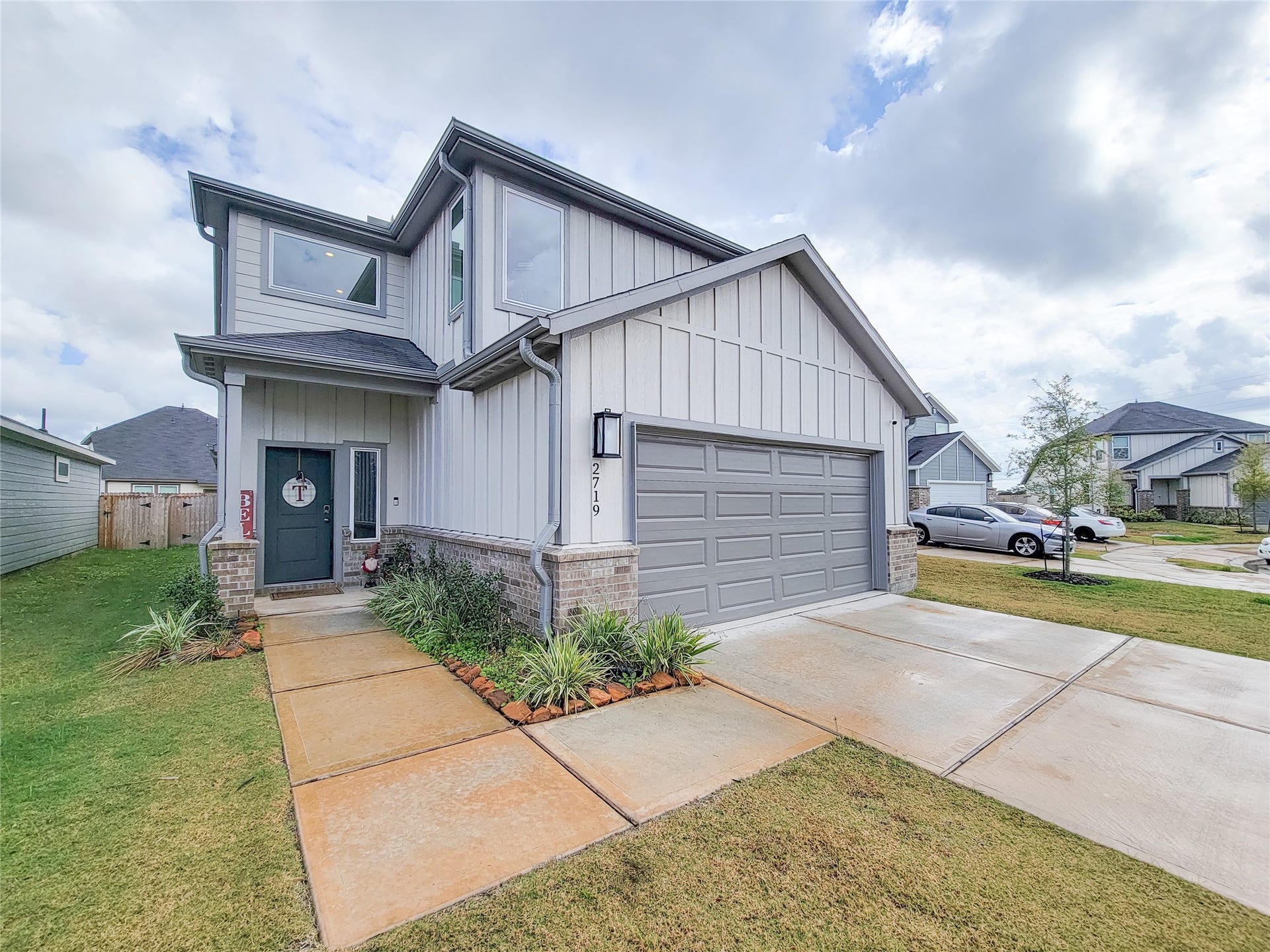 2719 Forest Retreat Lane, Missouri City, TX 77489 This modern two-story home features a clean gray facade with white trim, a spacious two-car garage, and a well-maintained front yard. The entrance is inviting with a pathway lined with greenery, set in a suburban neighborhood.