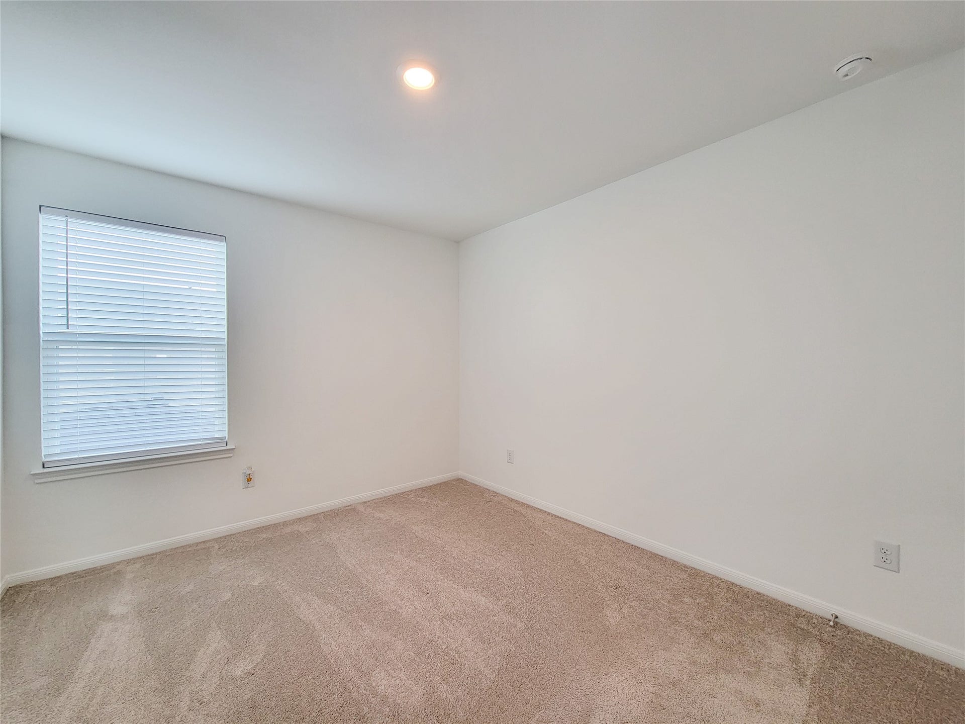 2719 Forest Retreat Lane, Missouri City, TX 77489 Bright, empty room with neutral carpet and white walls. A single window with blinds offers natural light, and there's a ceiling light fixture. Ideal as a bedroom or office space.