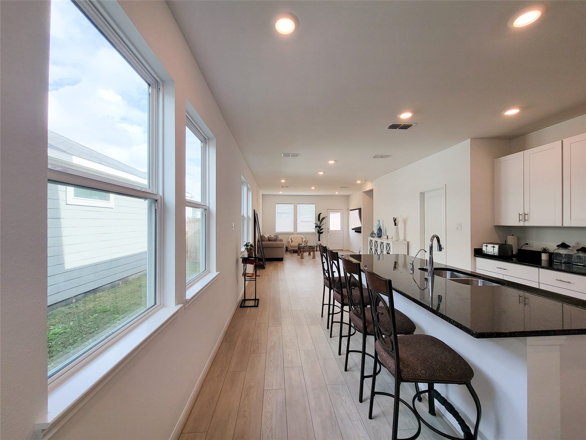 2719 Forest Retreat Lane, Missouri City, TX 77489 Bright and airy open-plan kitchen and living area with modern finishes. Features a large island with seating, recessed lighting, and ample windows providing natural light.