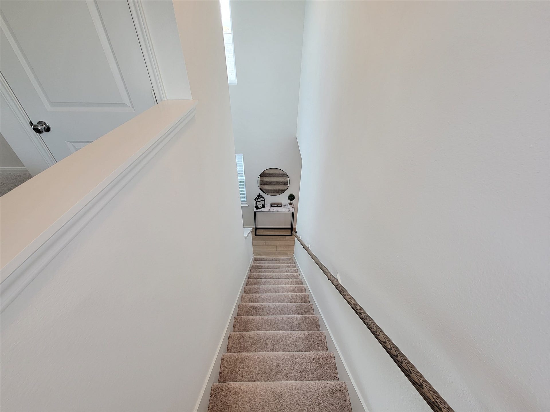 2719 Forest Retreat Lane, Missouri City, TX 77489 A well-lit staircase with carpeted steps and a wooden handrail leads down to a landing area. The walls are painted white, giving a clean and modern look.
