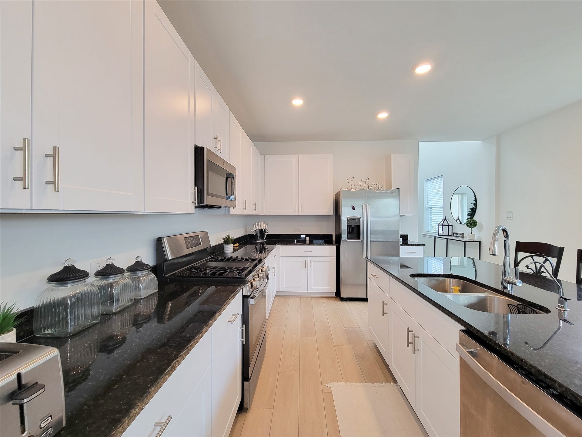 2719 Forest Retreat Lane, Missouri City, TX 77489 This modern kitchen features sleek white cabinetry, black granite countertops, and stainless steel appliances, including a double oven and fridge. The open layout and ample lighting create a bright, inviting space perfect for cooking and entertaining.