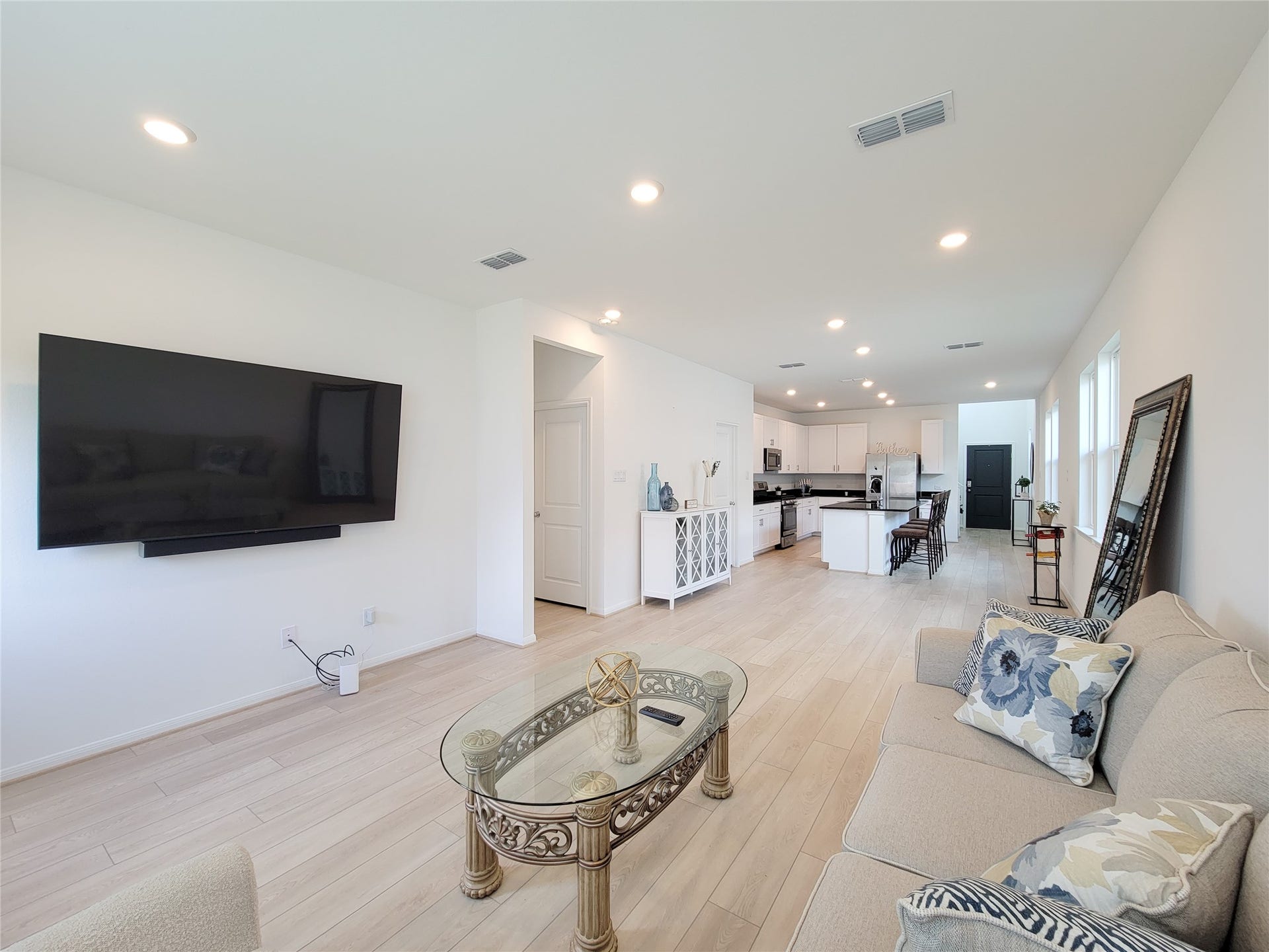 2719 Forest Retreat Lane, Missouri City, TX 77489 This spacious open-concept living area features a modern kitchen with sleek white cabinets and a large island. Ample natural light streams through multiple windows, enhancing the bright and inviting atmosphere.