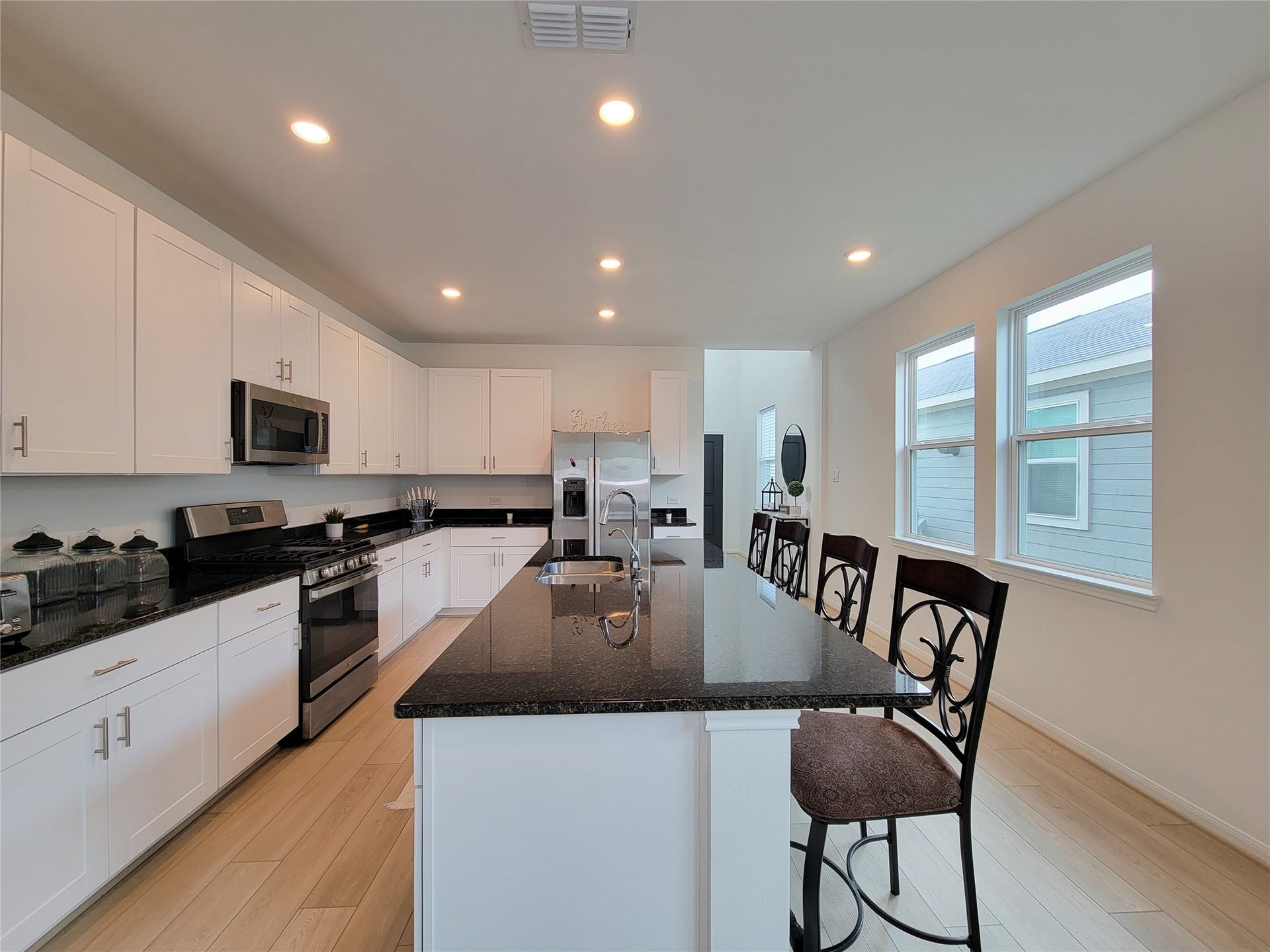 2719 Forest Retreat Lane, Missouri City, TX 77489 This kitchen features a modern design with white cabinetry, a sleek black granite countertop island, stainless steel appliances, and ample natural light from large windows. Perfect for entertaining and cooking.