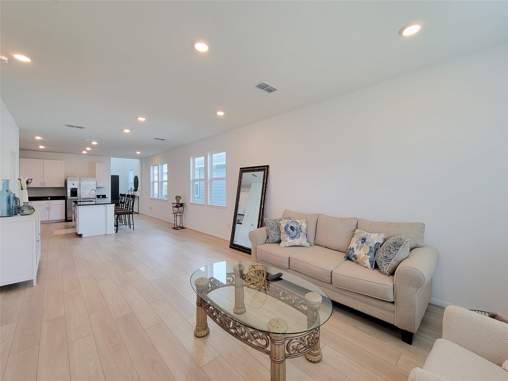 2719 Forest Retreat Lane, Missouri City, TX 77489 Spacious, open-concept living area with light wood flooring and a modern kitchen. There's ample natural light from large windows.
