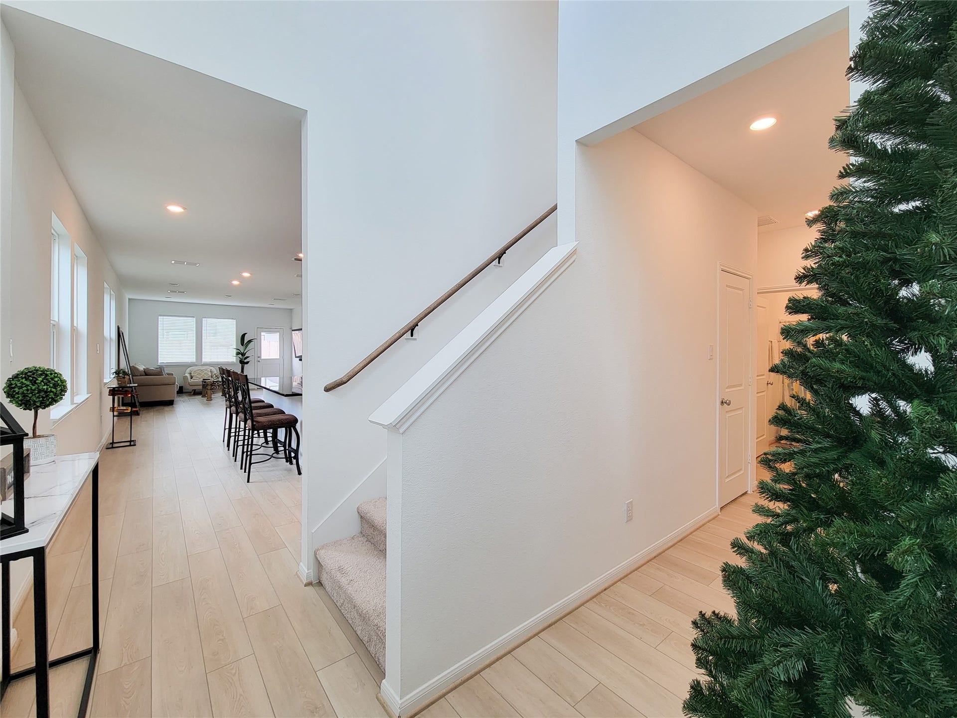 2719 Forest Retreat Lane, Missouri City, TX 77489 Open entryway with light wood flooring and a staircase leading up. The space flows into a well-lit living area with large windows and a dining section, providing an inviting atmosphere.