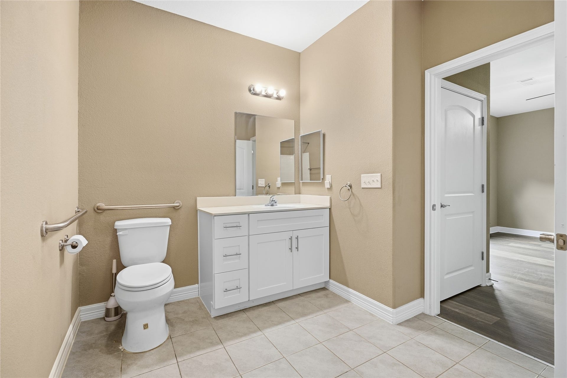 102 20th Avenue N, Texas City, TX 77590 The private primary bathroom features a white vanity with drawer and cabinet storage, plus grab bars beside the toilet.
