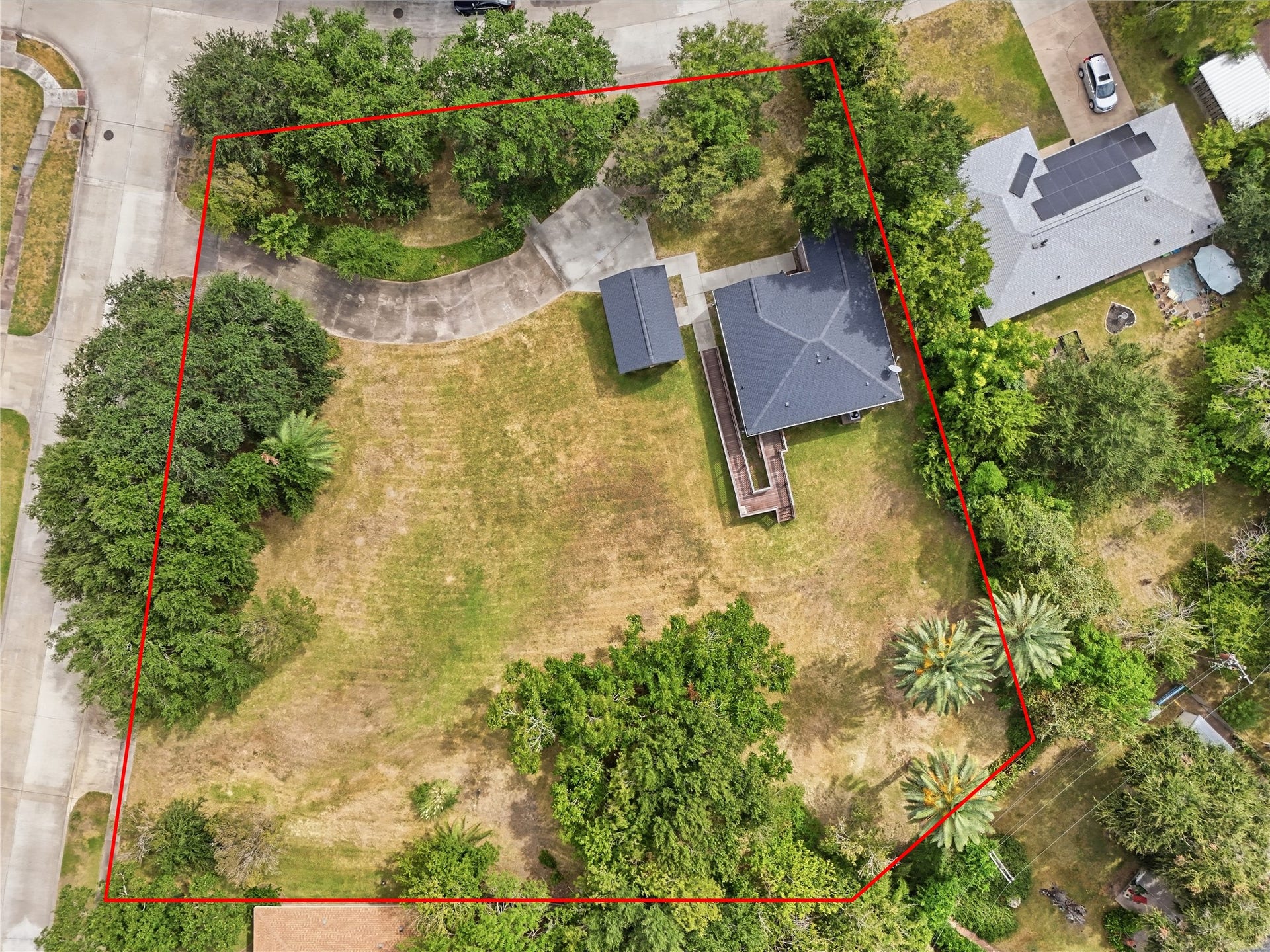 102 20th Avenue N, Texas City, TX 77590 An overhead view highlights the spacious corner lot, with mature trees, open yard space, and a curved driveway leading to the detached garage.