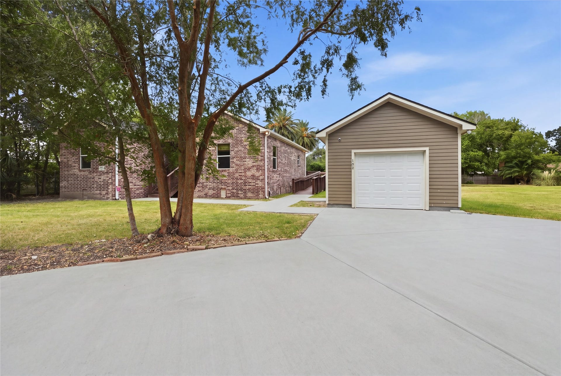 102 20th Avenue N, Texas City, TX 77590 Detached garage with a wide circle concrete driveway offering additional parking. A walkway leads to the homes side access ramp.