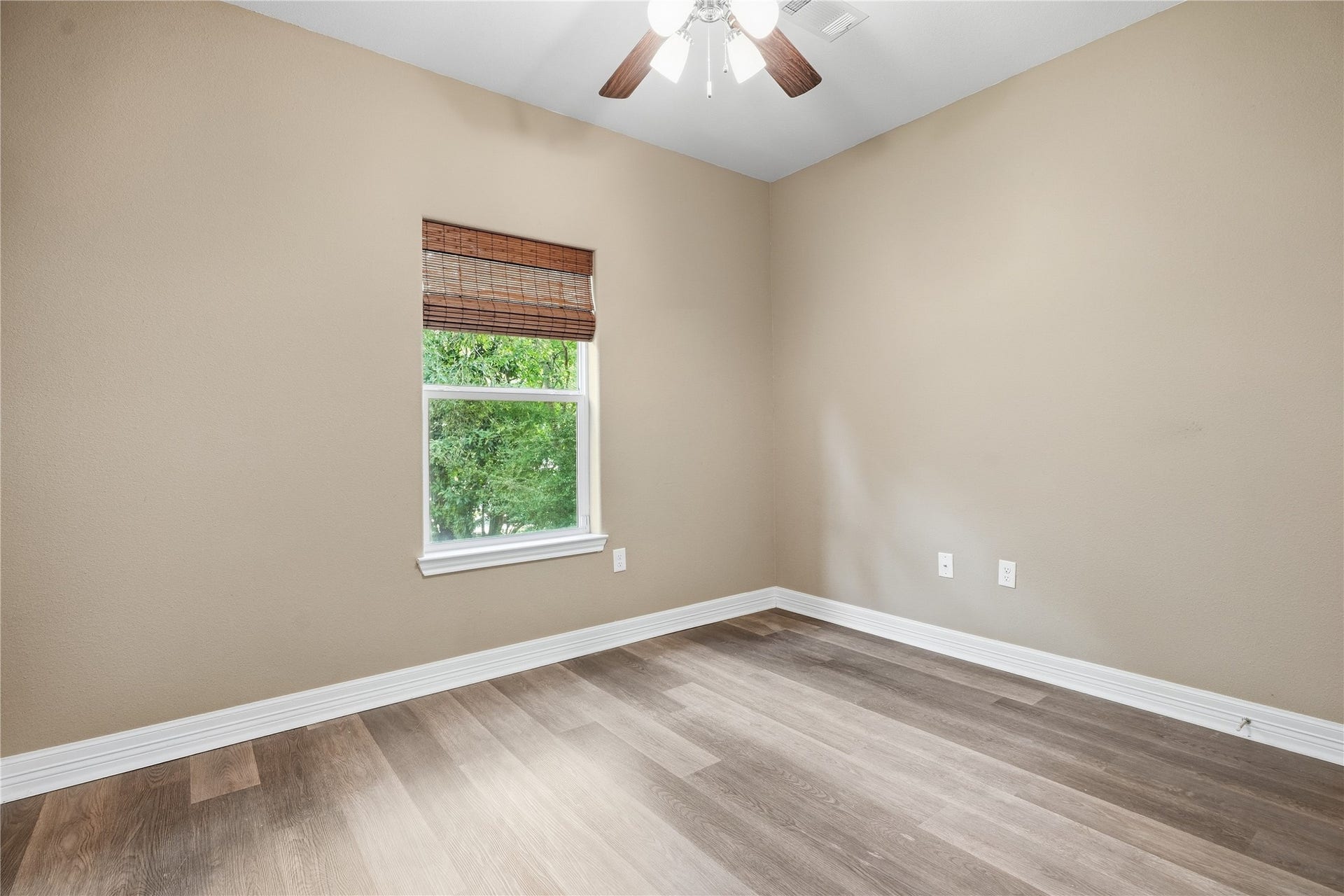 102 20th Avenue N, Texas City, TX 77590 Natural light and a view of the trees brighten this secondary bedroom, featuring neutral colors and a ceiling fan.