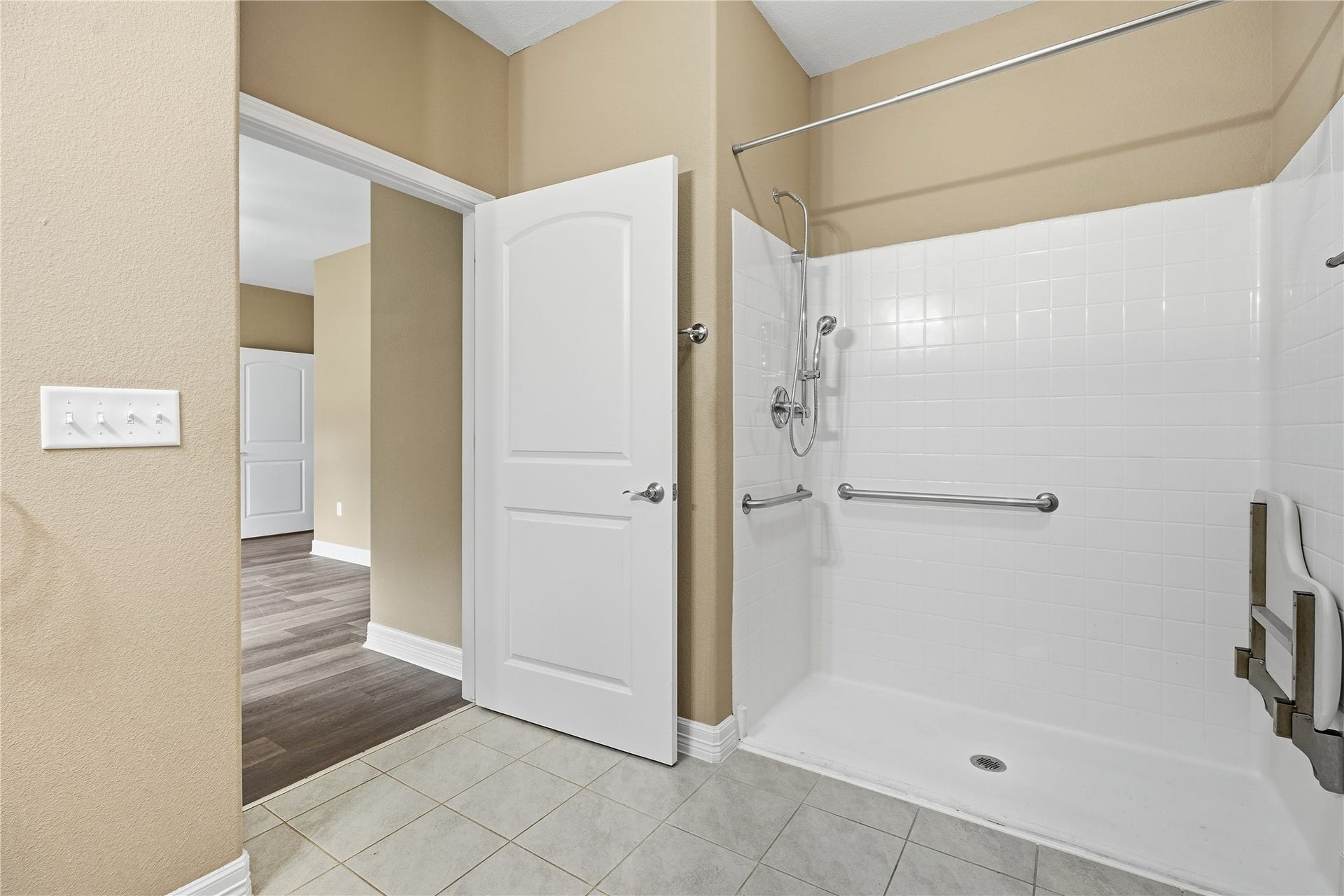 102 20th Avenue N, Texas City, TX 77590 The primary bathroom offers accessibility features including a spacious shower with a handheld showerhead, grab bars, and a fold-down seat.