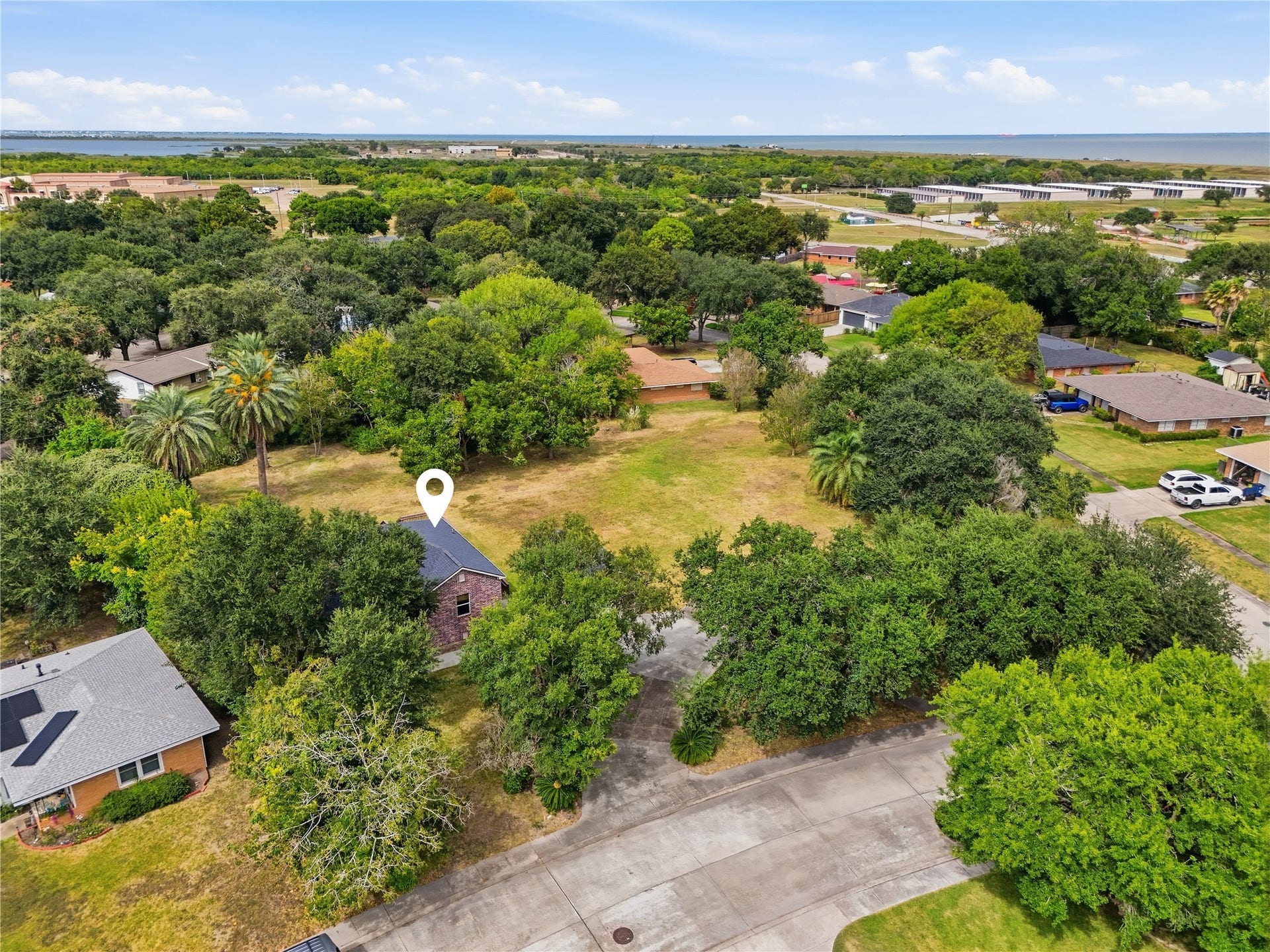 102 20th Avenue N, Texas City, TX 77590 An aerial view of the home and spacious yard, with mature trees and the bay visible in the distance.