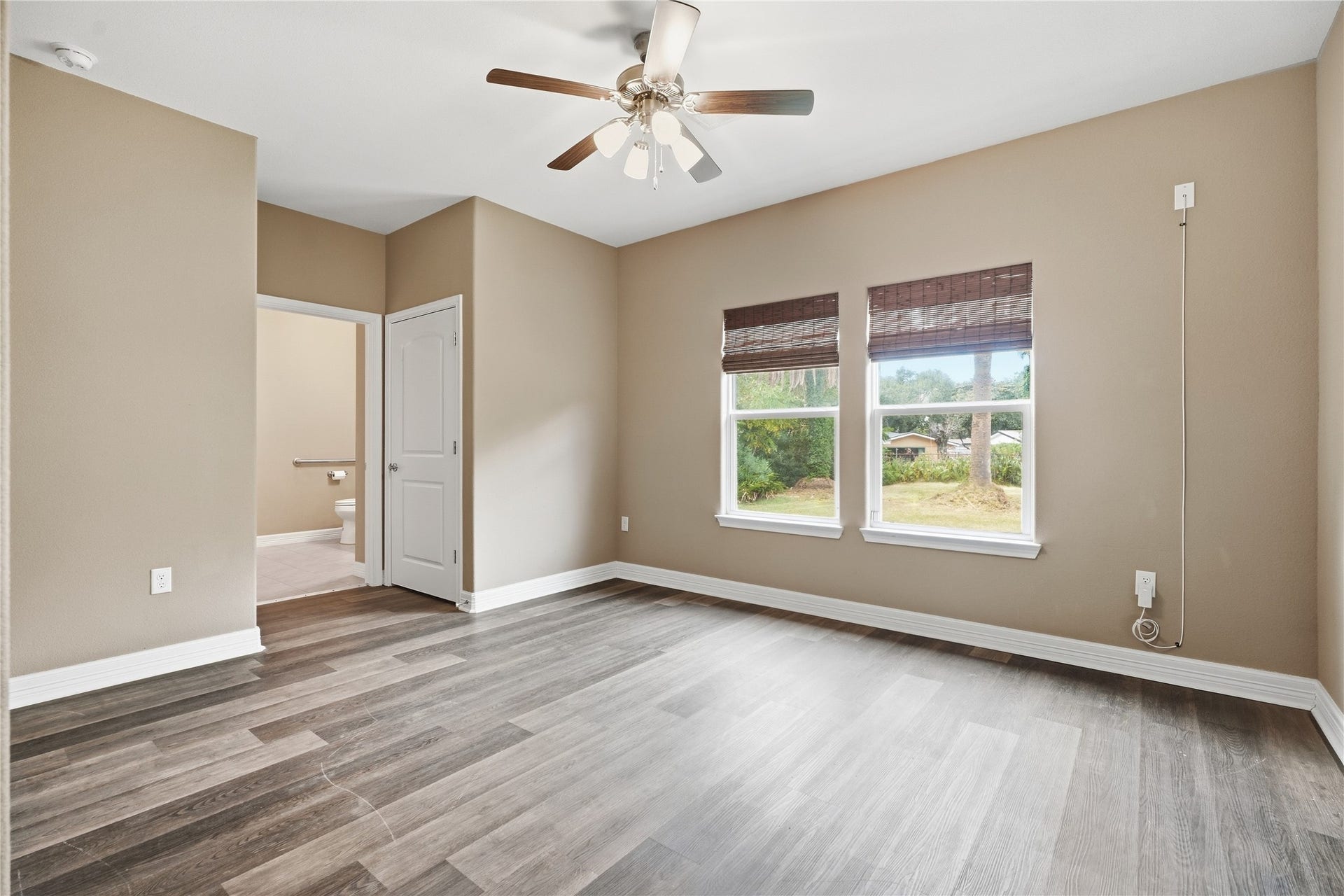 102 20th Avenue N, Texas City, TX 77590 Two windows overlooking the backyard bring natural light into the primary bedroom, which features a ceiling fan and a private bathroom.