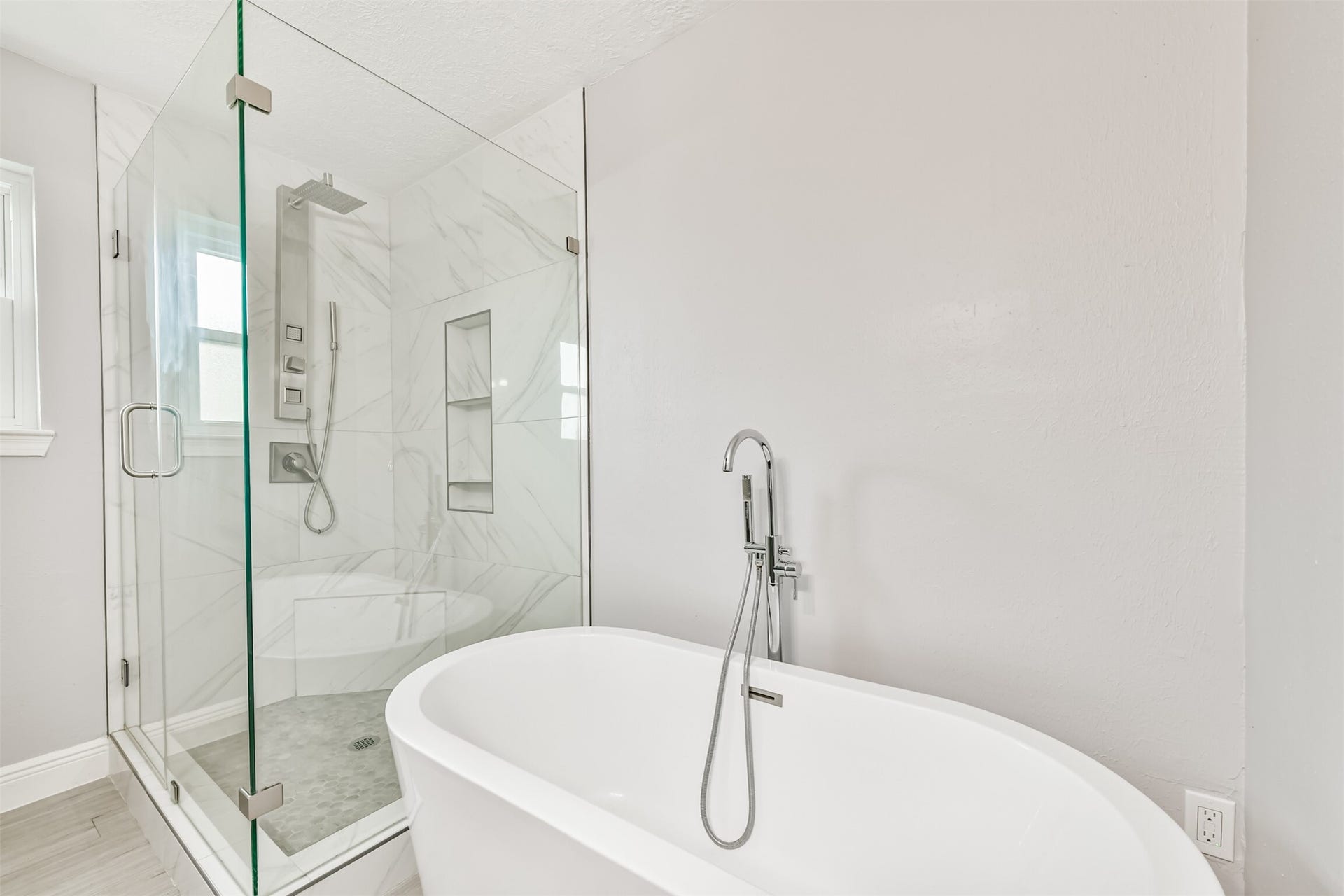 9311 Masters Road, Manvel, TX 77578 Experience luxury in this primary bath, featuring a modern freestanding tub and a sleek glass-enclosed shower with elegant tilework.