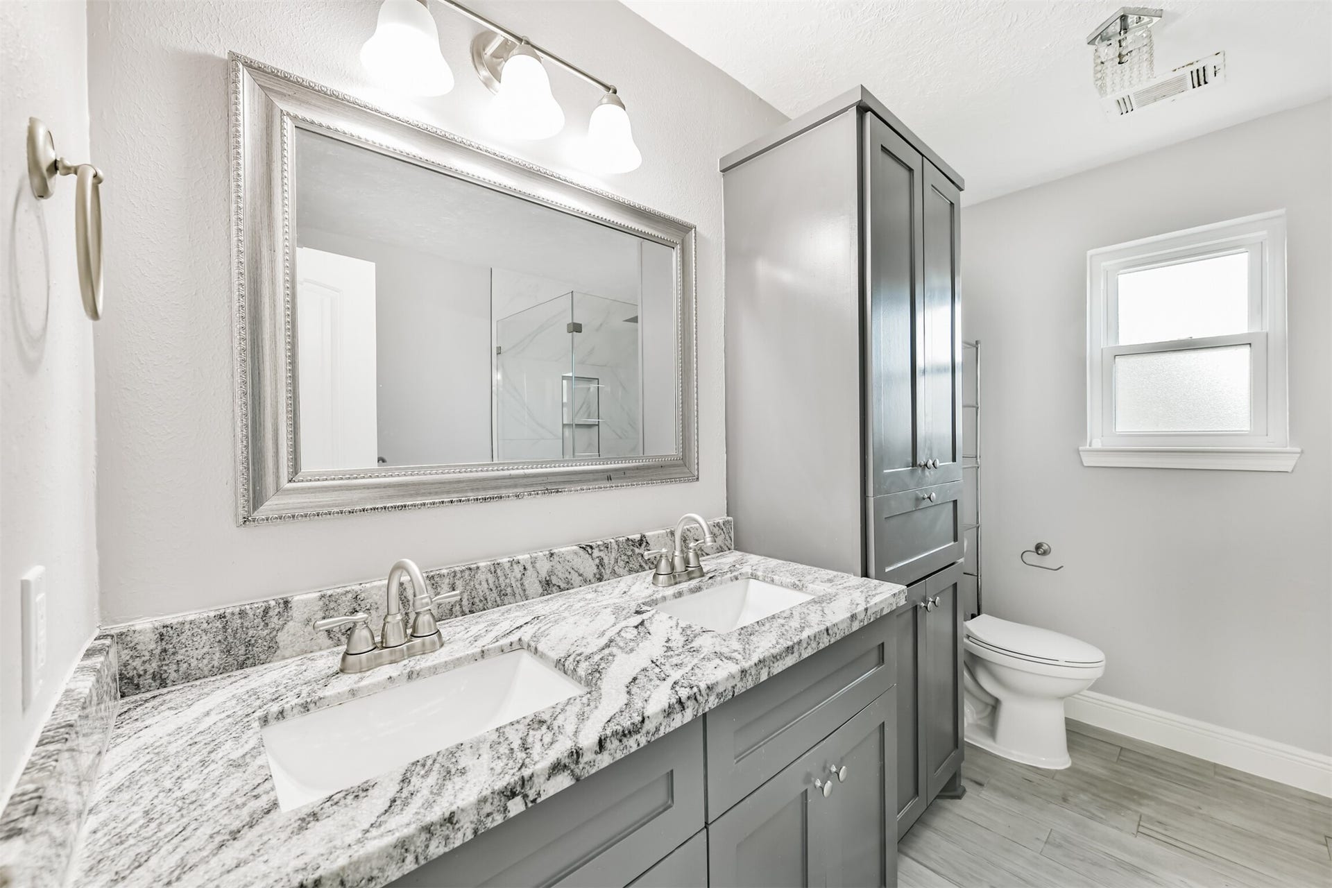 9311 Masters Road, Manvel, TX 77578 Experience luxury in the primary bath featuring dual sinks with elegant granite countertops, modern fixtures, and ample storage, all bathed in natural light.