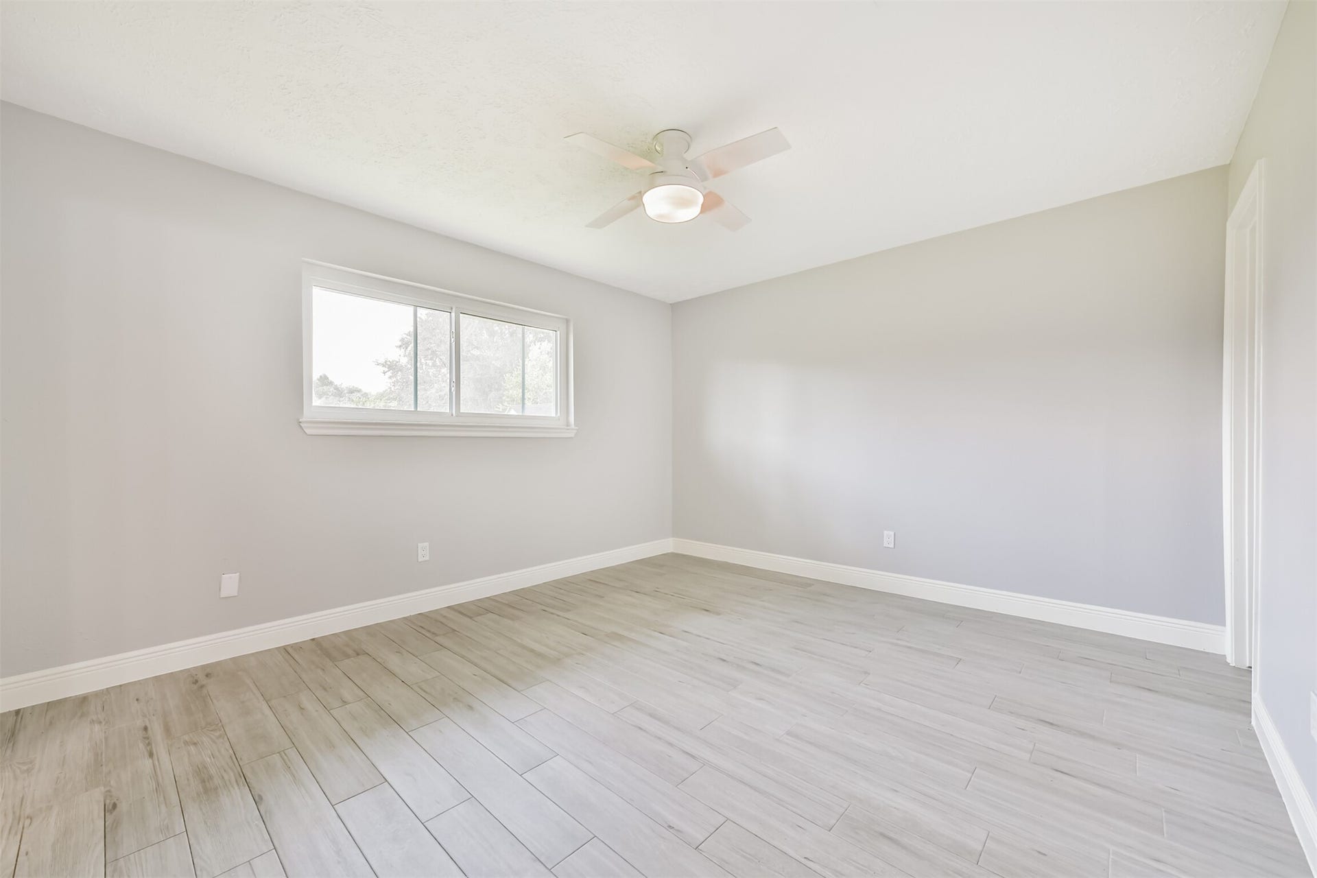 9311 Masters Road, Manvel, TX 77578 Spacious primary bedroom featuring sleek flooring, abundant natural light, and a stylish ceiling fan.