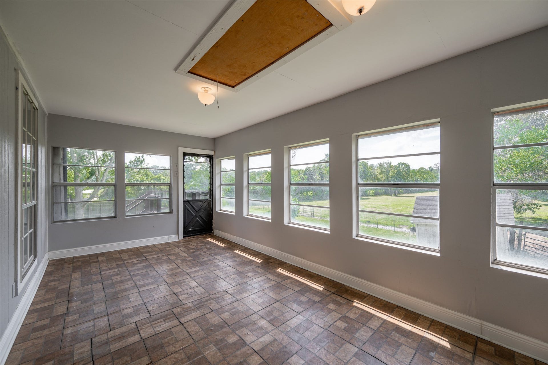 9311 Masters Road, Manvel, TX 77578 Experience relaxation in this inviting sunroom, featuring elegant wood beams, a cozy brick fireplace, and abundant natural light through large windows. Perfect for unwinding and enjoying serene views.