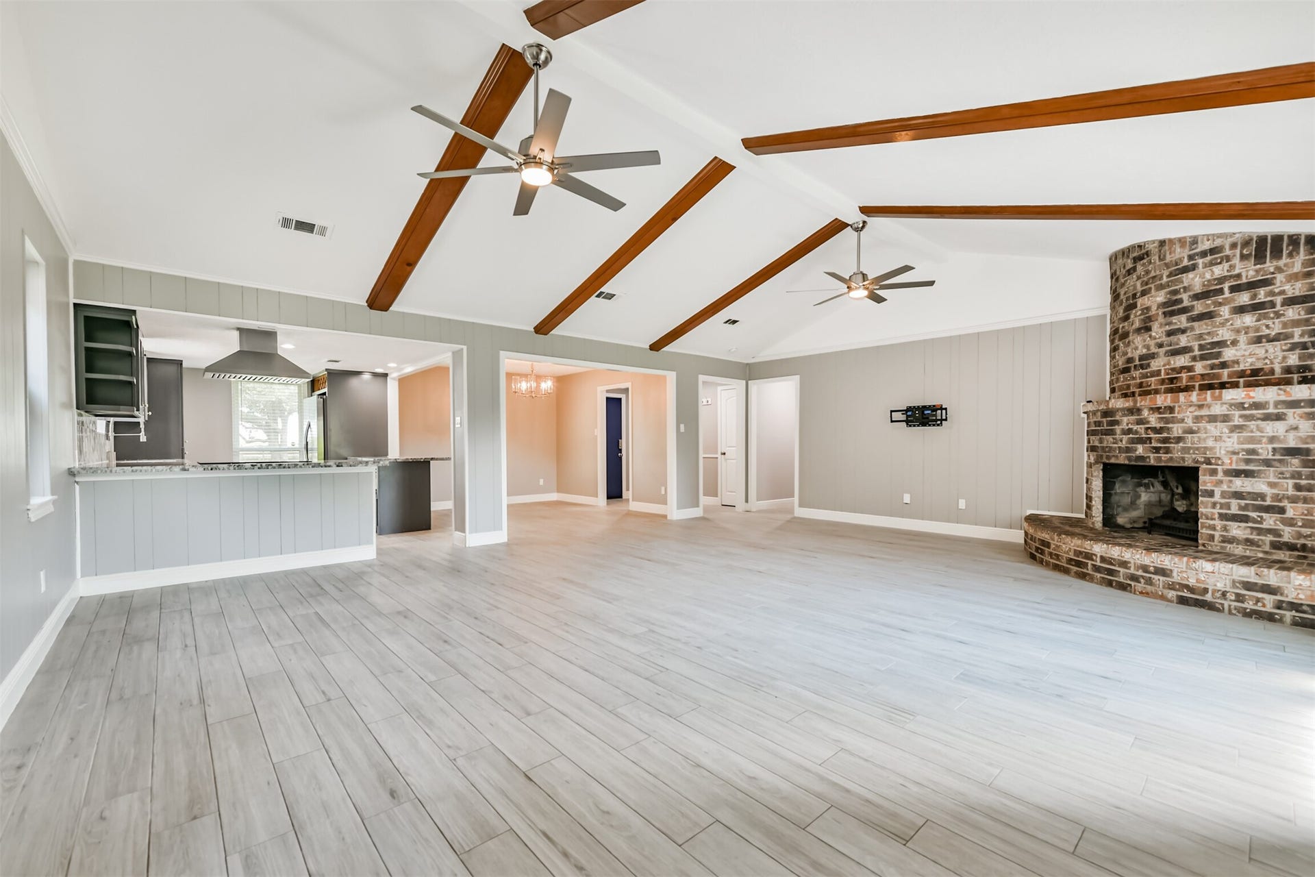 9311 Masters Road, Manvel, TX 77578 Spacious and inviting living area featuring vaulted ceilings, elegant wood beams, and a striking brick fireplace. Perfect for modern living and entertaining.