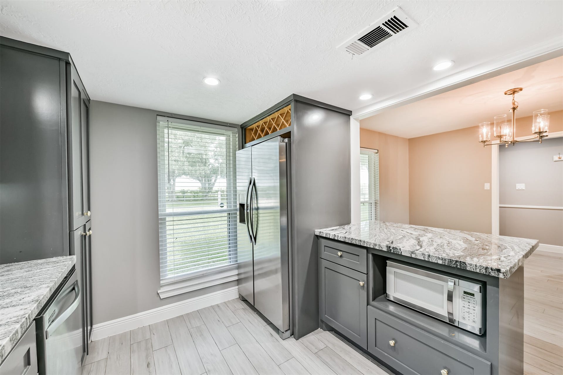 9311 Masters Road, Manvel, TX 77578 Modern kitchen featuring sleek cabinetry, stainless steel appliances, and elegant granite countertops, seamlessly flowing into the dining area.