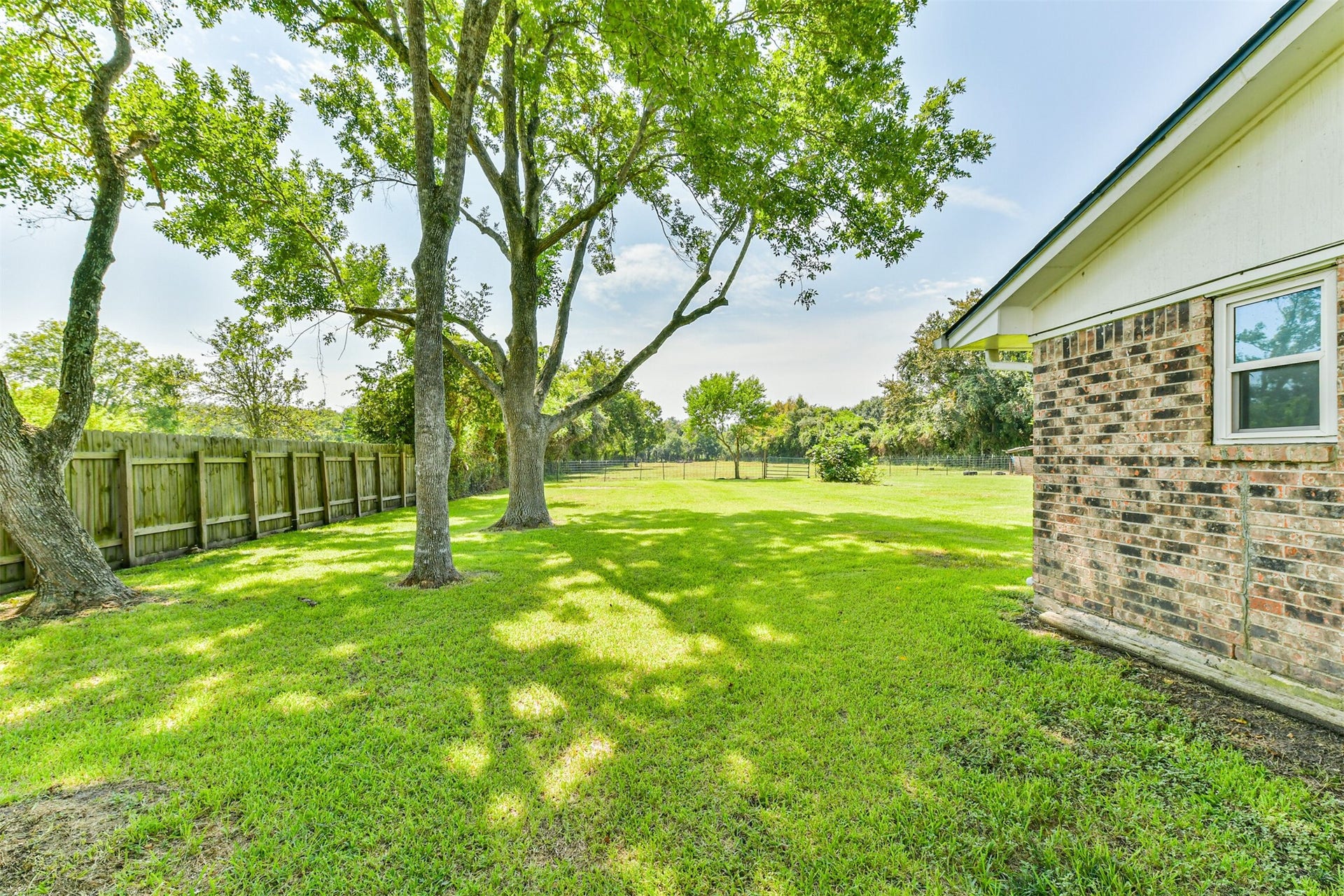 9311 Masters Road, Manvel, TX 77578 Expansive side yard with lush greenery and mature trees, perfect for relaxation and outdoor activities.