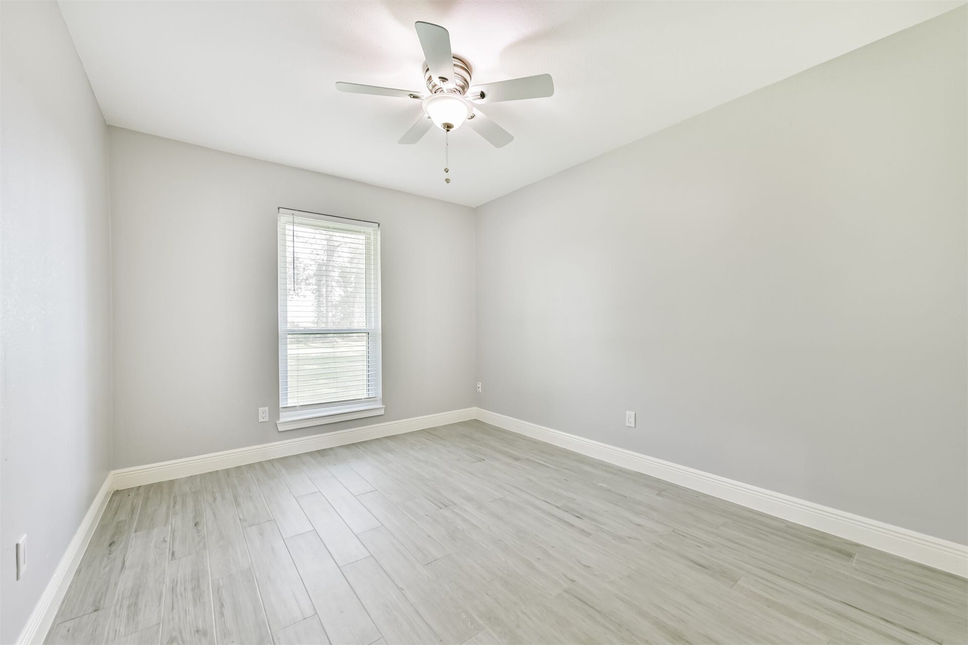 9311 Masters Road, Manvel, TX 77578 Spacious and bright bedroom featuring elegant wood flooring and a large window for natural light.