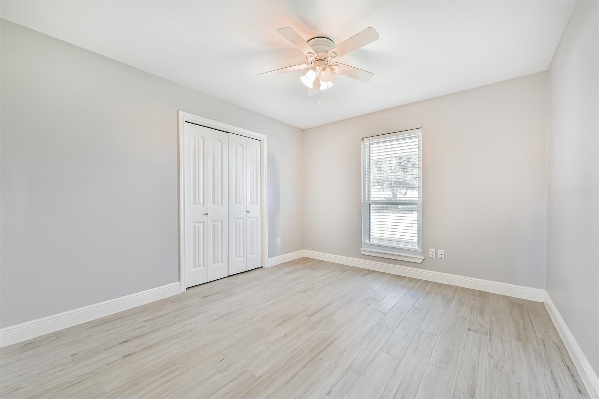 9311 Masters Road, Manvel, TX 77578 Bright and airy second bedroom featuring sleek flooring, a ceiling fan, and a spacious closet, perfect for comfort and functionality.