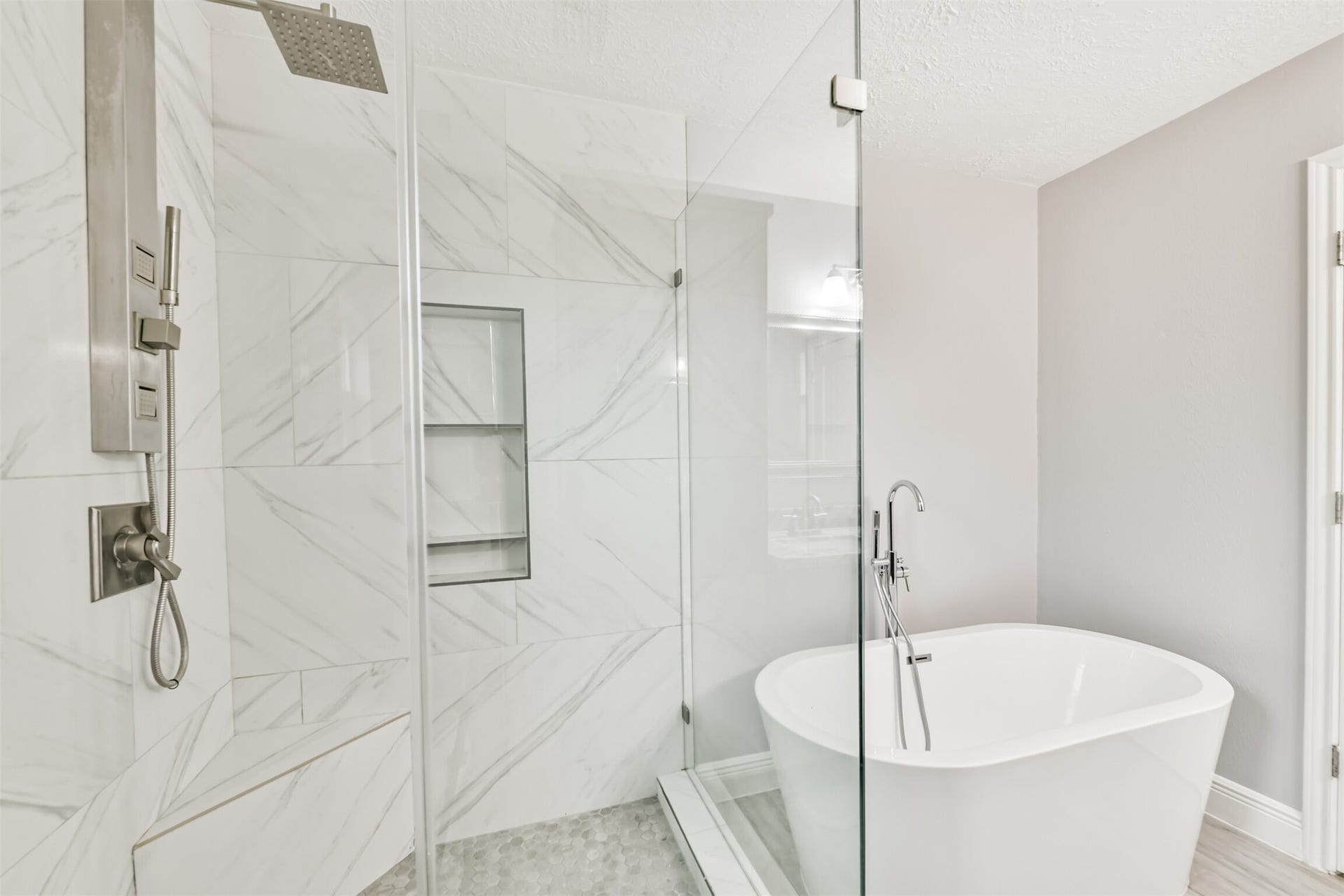 9311 Masters Road, Manvel, TX 77578 Luxurious primary bath featuring a sleek glass-enclosed shower, elegant marble tiles, and a modern freestanding tub for ultimate relaxation.