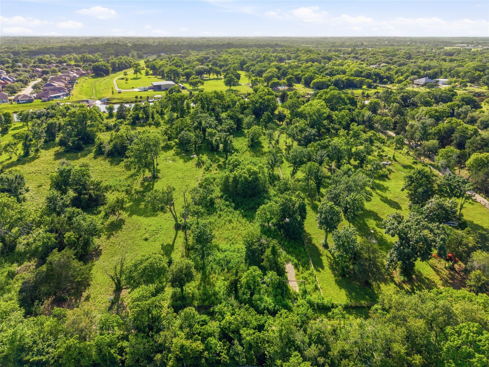7326 Custer Street, Hitchcock, TX 77563 This aerial photo showcases a lush, green landscape with scattered trees and open grassy areas.