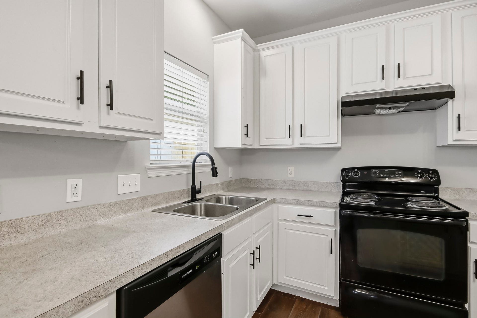 10023 Checkerberry Park Lane, Tomball, TX 77375 This close-up view highlights an efficient cooking zone featuring ample counter space, a double-basin stainless steel sink, and a gooseneck faucet positioned right by a bright window.