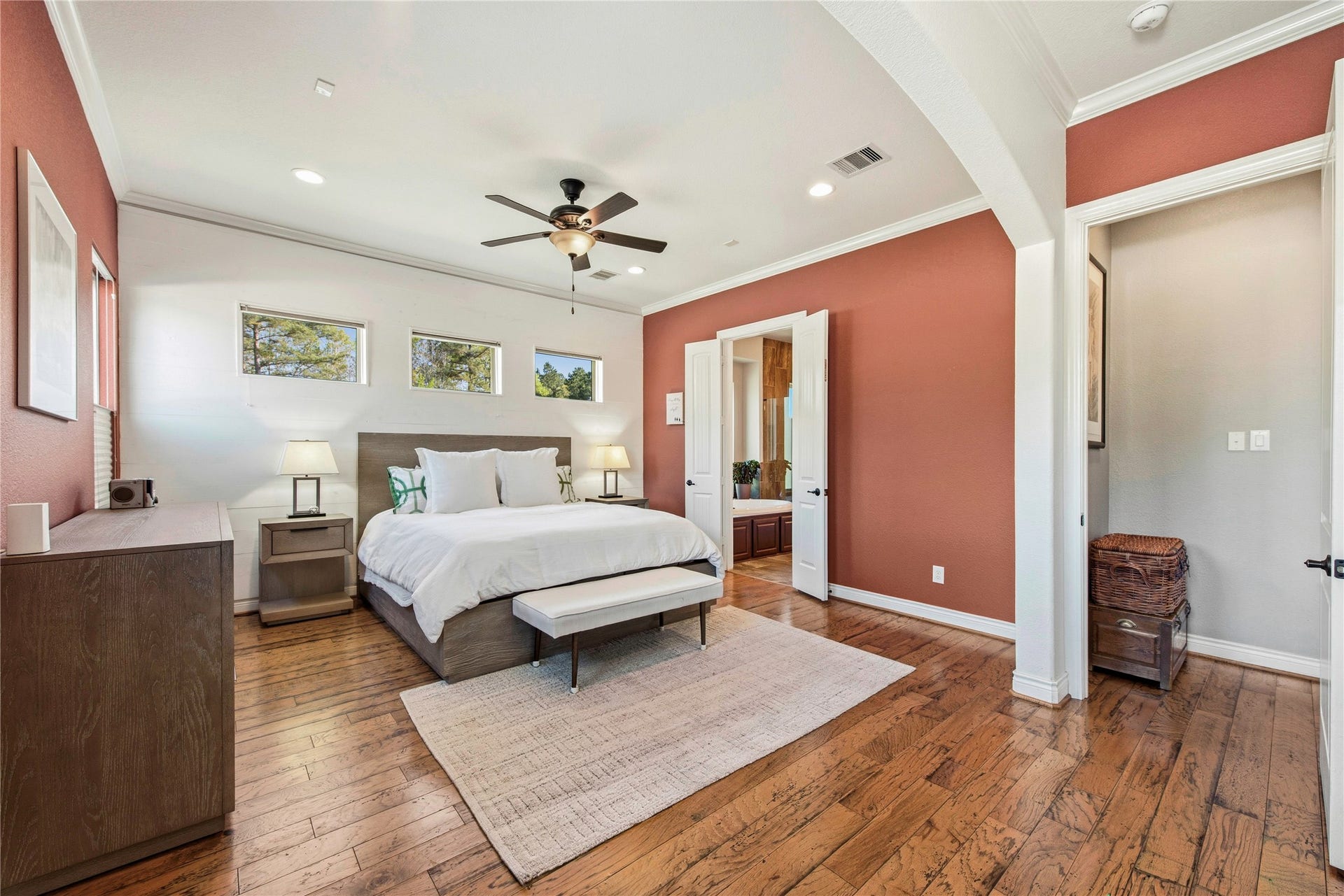 Primary bedroom showcasing hardwood floors, ceiling fan and spacious sitting area.