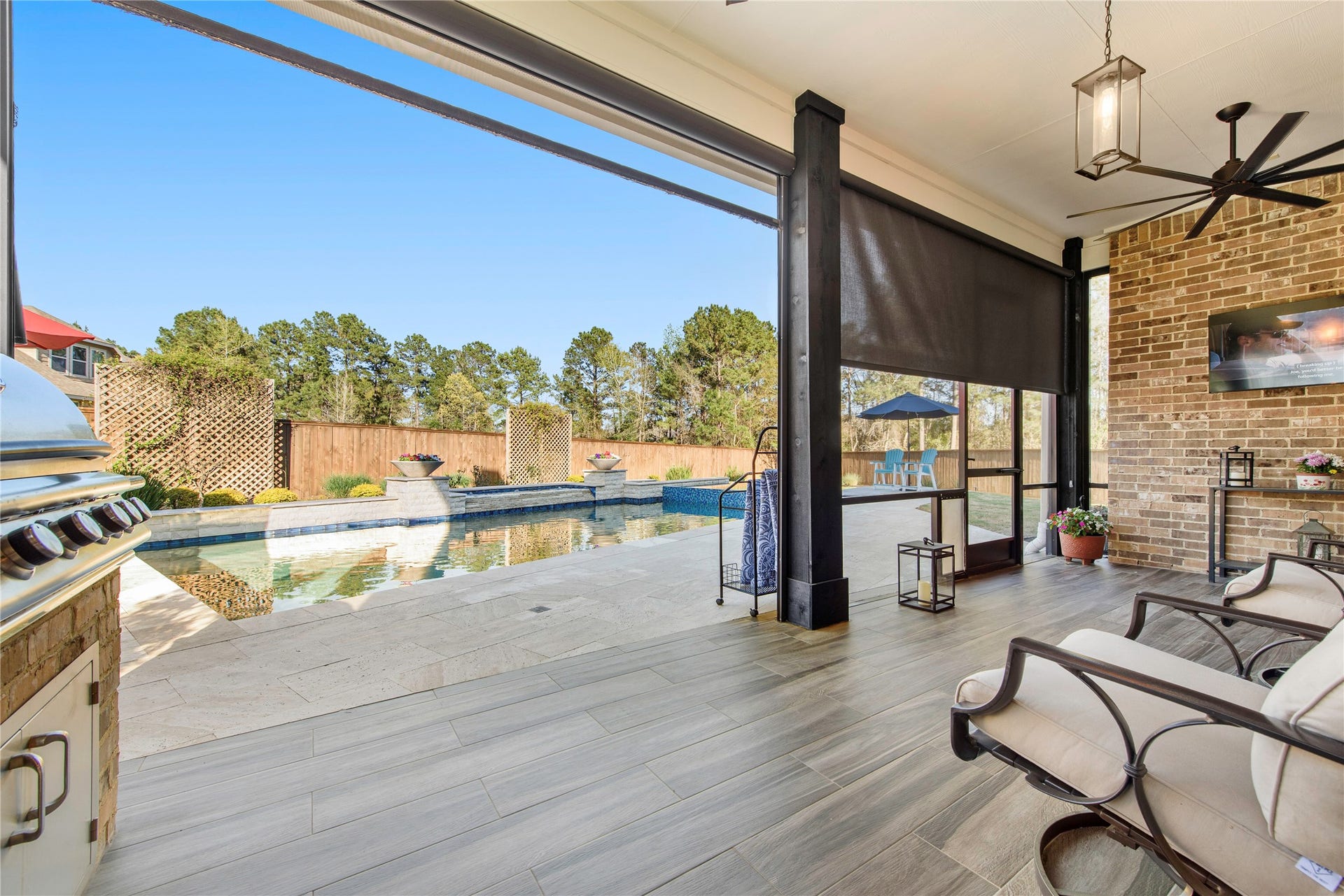 Covered outdoor living area overlooking the pool and beautifully landscaped backyard.
