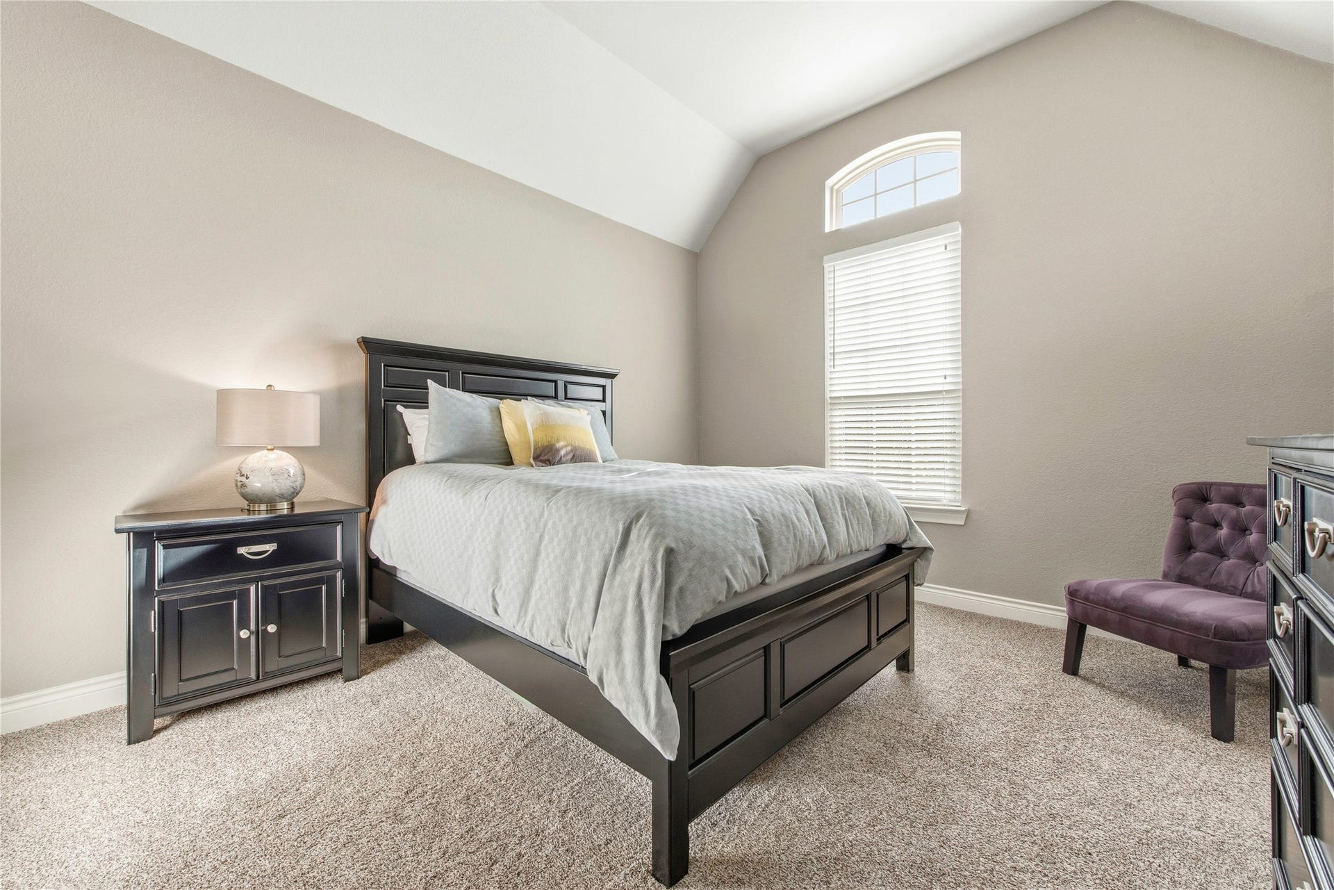 Spacious secondary bedroom featuring vaulted ceilings, hardwood flooring and natural light.