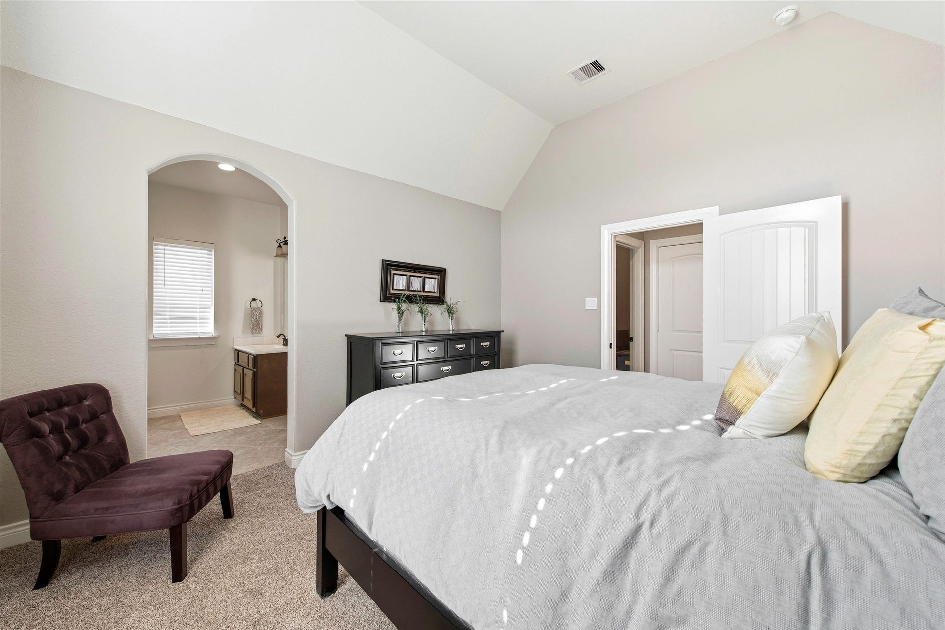 Bright bedroom featuring neutral finishes, spacious layout and comfortable seating area.