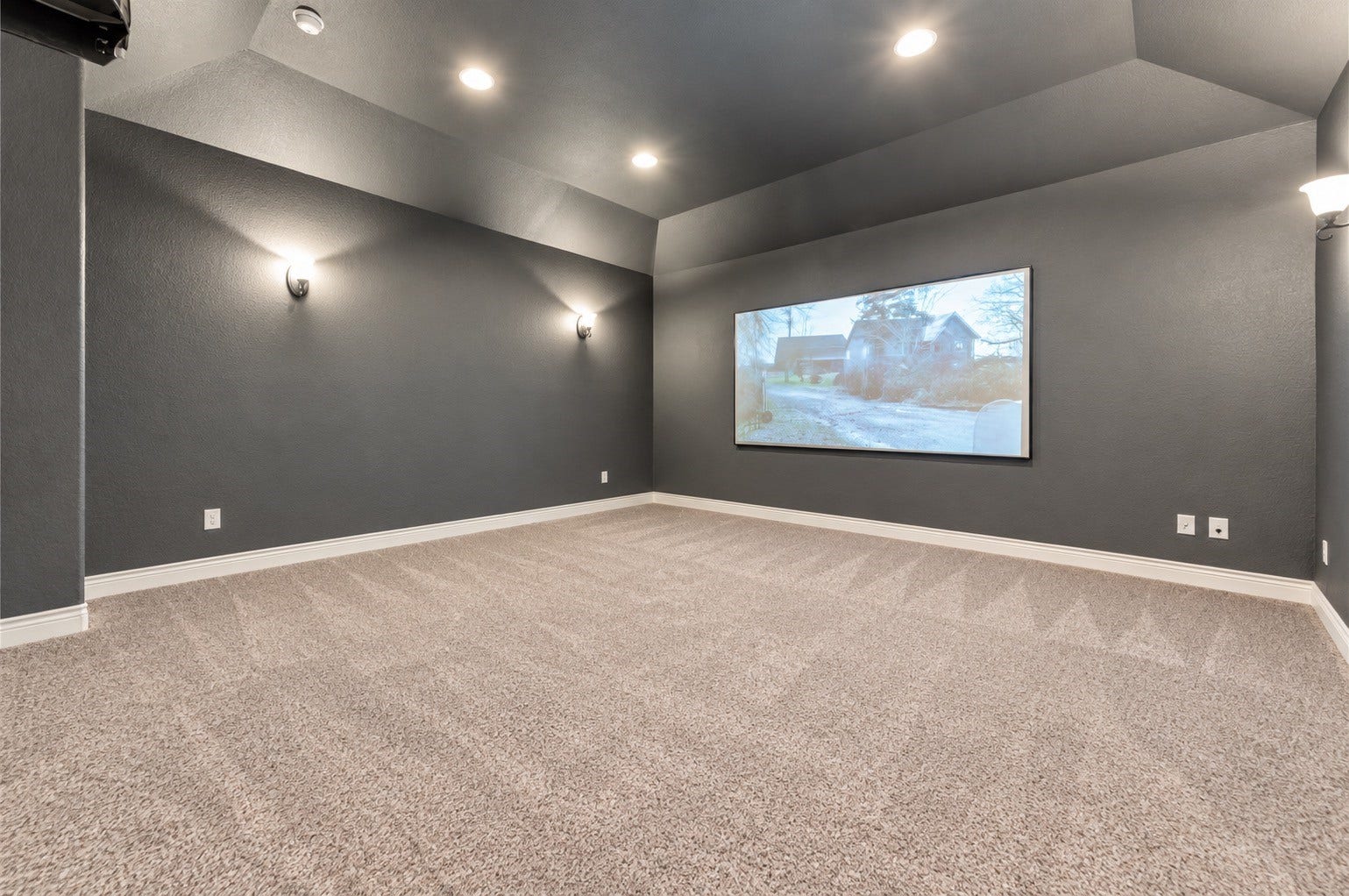 Spacious media room featuring comfortable seating, large screen and recessed lighting.