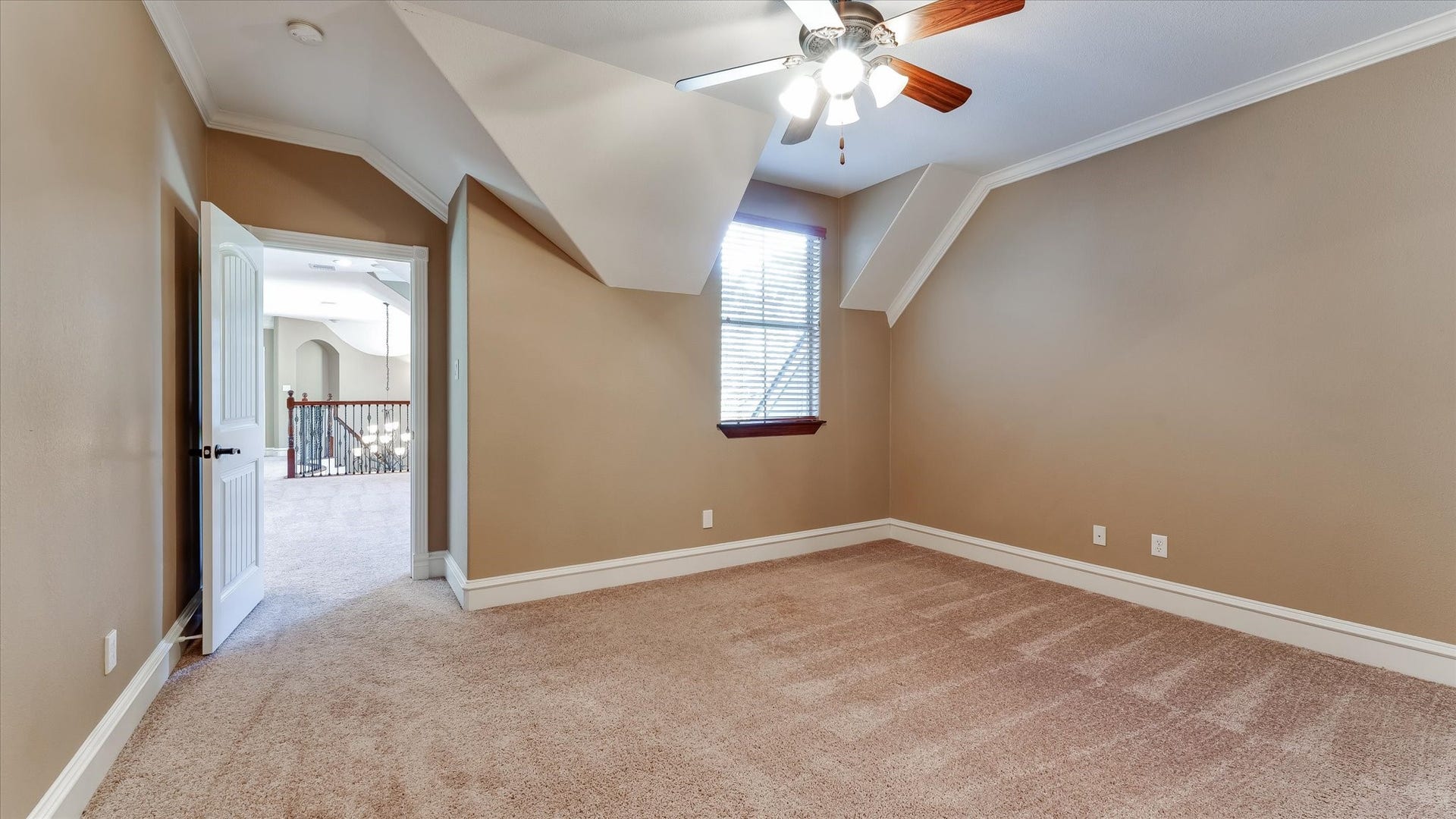 8071 Stacy Diane Drive, Montgomery, TX 77316 This room features neutral walls, carpeted flooring, and a ceiling fan with light. A window provides natural light, and there's an open doorway leading to a hallway with a view of a railing. The space feels bright and cozy, ideal for a bedroom or office.