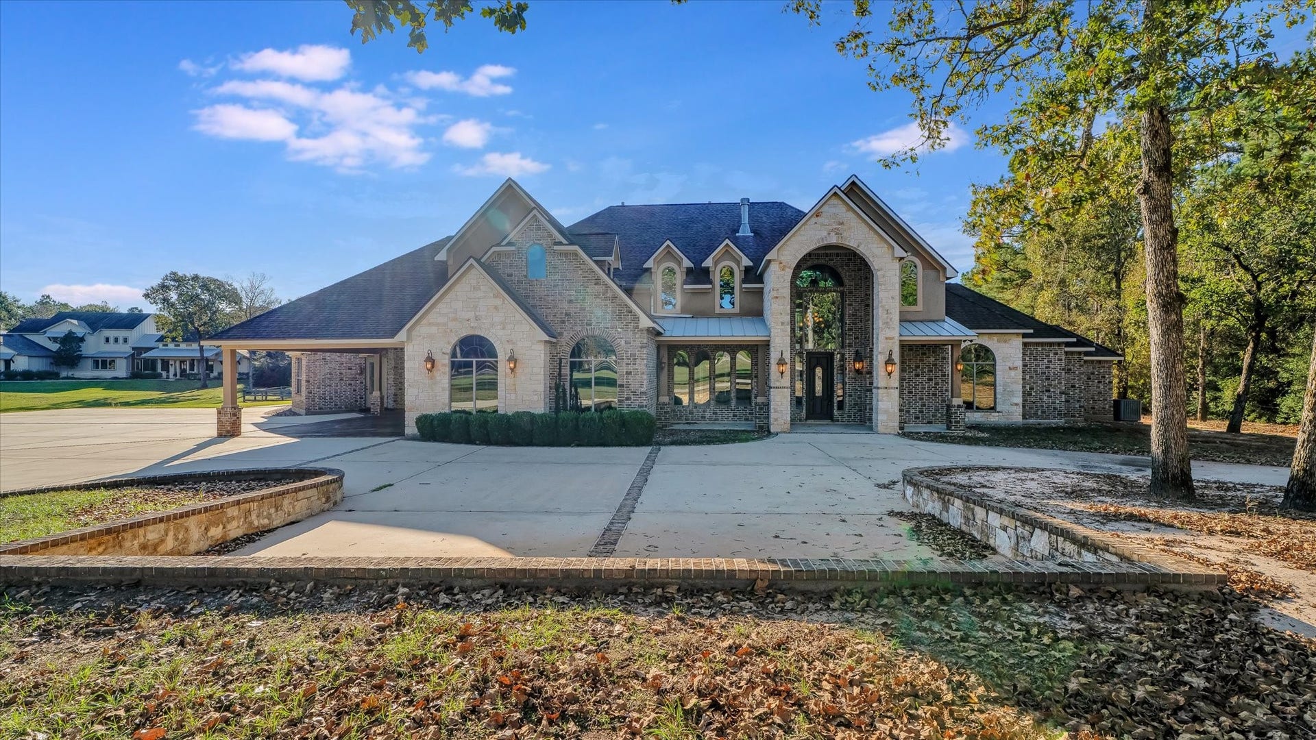 8071 Stacy Diane Drive, Montgomery, TX 77316 This image shows a spacious, brick and stone home with a large driveway and elegant arched windows. Surrounded by trees, it offers a serene and private setting. The exterior design combines classic and contemporary elements, making it an attractive option for buyers seeking both style and functionality.