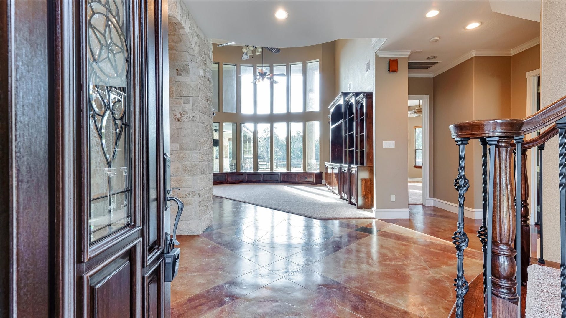 8071 Stacy Diane Drive, Montgomery, TX 77316 This photo showcases a spacious, elegant entryway with a blend of stone and wood accents. The open floor plan features high ceilings and large windows that provide ample natural light. The polished floors and staircase add to the luxurious feel, while the built-in shelving offers functional space.