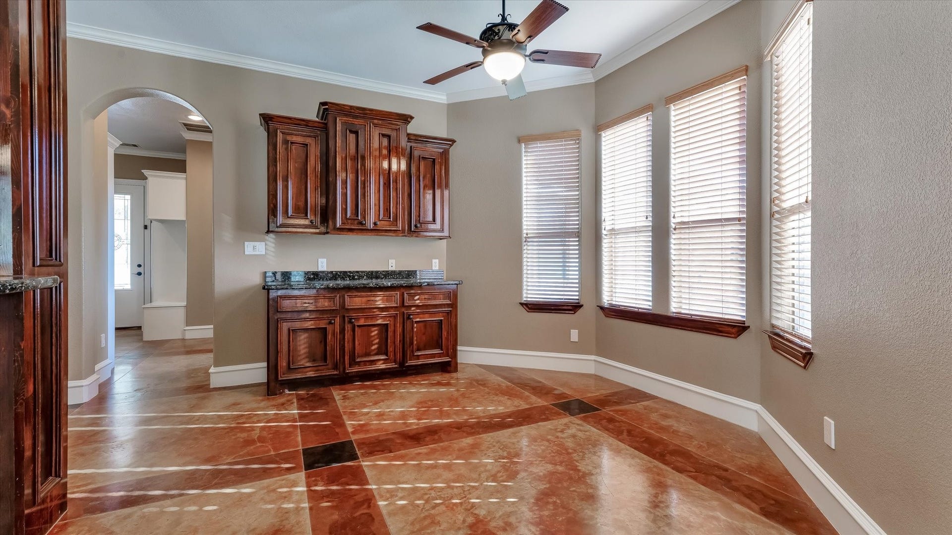 8071 Stacy Diane Drive, Montgomery, TX 77316 This room features elegant tile flooring and ample natural light from multiple windows with blinds. It includes a ceiling fan and rich wooden cabinetry with granite countertops, perfect for dining or as a multipurpose space. An arched doorway adds architectural interest.