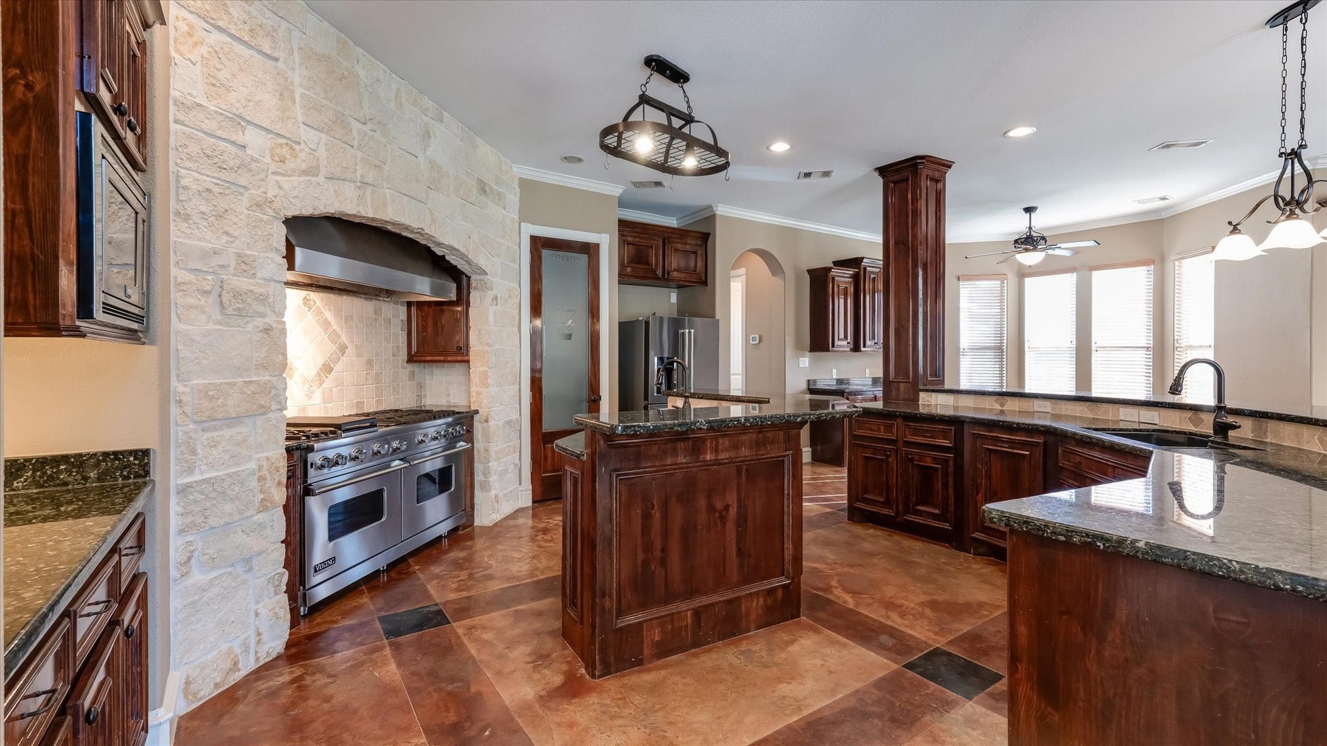 8071 Stacy Diane Drive, Montgomery, TX 77316 This kitchen features a spacious, open layout with rich wood cabinetry, stone accents, and modern appliances. The large island offers plenty of counter space, and ample natural light filters through multiple windows. Ideal for entertaining and culinary enthusiasts.