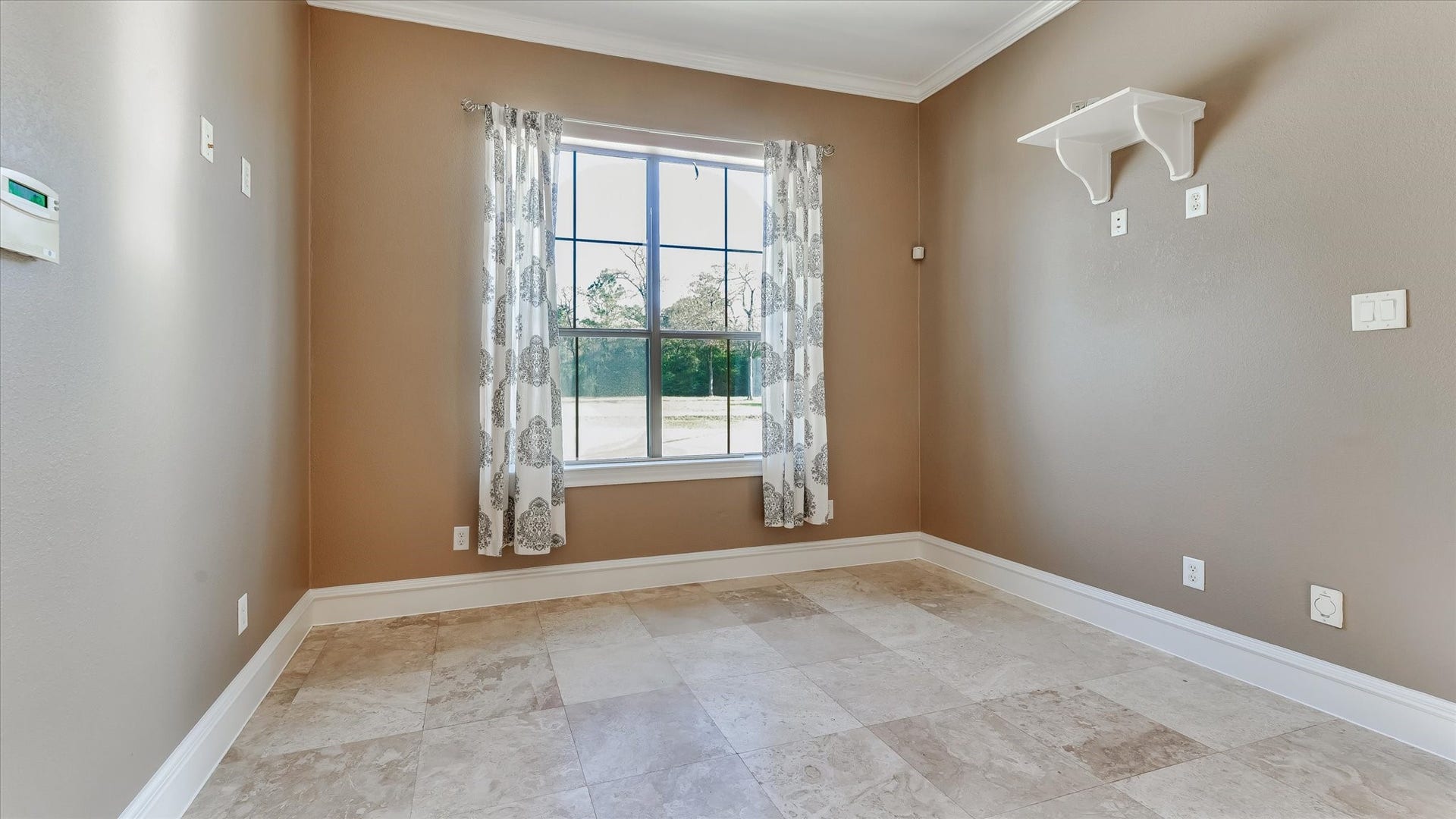 8071 Stacy Diane Drive, Montgomery, TX 77316 This room features neutral-toned walls and tiled flooring, with a large window offering natural light. It includes a small wall shelf and elegant curtains, creating a cozy and versatile space.