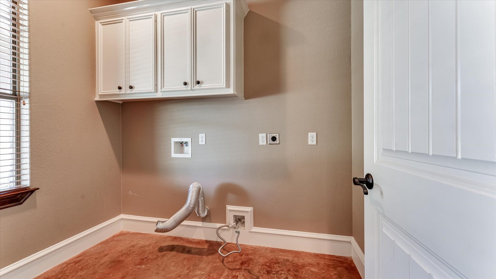 8071 Stacy Diane Drive, Montgomery, TX 77316 This photo shows a laundry room with a clean, neutral color scheme. It features upper cabinetry for storage, hookups for a washer and dryer, and a window for natural light.