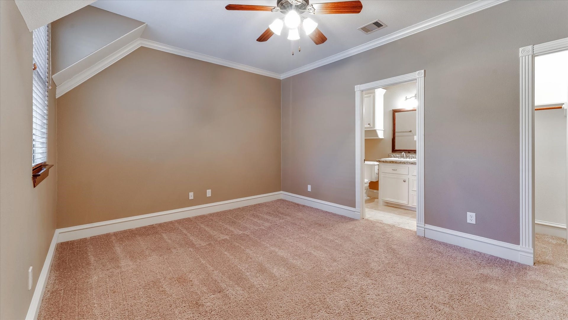 8071 Stacy Diane Drive, Montgomery, TX 77316 This is a cozy, carpeted bedroom with neutral walls and a ceiling fan. It features an angled ceiling, a window for natural light, and connects to a bathroom with a vanity and closet space.