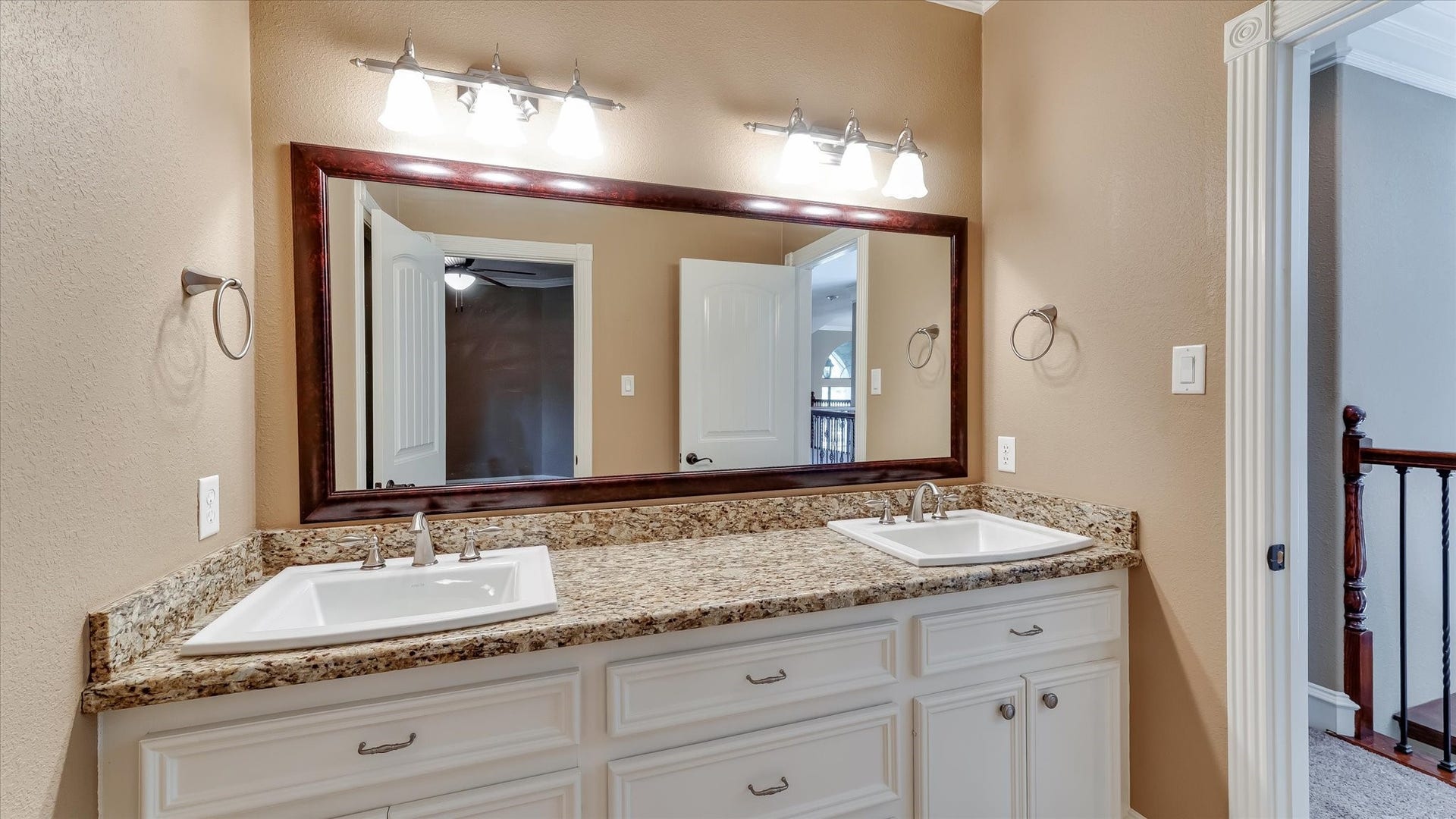 8071 Stacy Diane Drive, Montgomery, TX 77316 This bathroom features a double sink vanity with granite countertops, large mirror, and elegant lighting. The neutral wall color and white cabinetry create a clean, modern look.