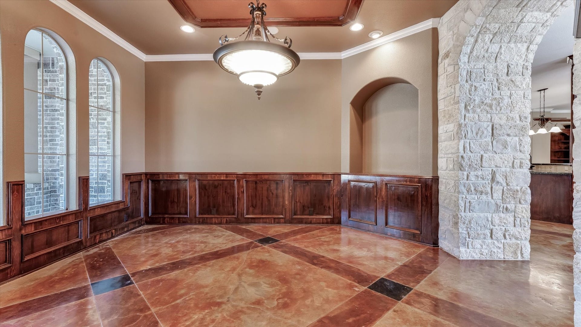 8071 Stacy Diane Drive, Montgomery, TX 77316 This room features elegant arched windows and a beautiful chandelier, complemented by rich wooden paneling. The floor has a warm, polished finish, and a stone archway leads to an adjoining space. Perfect for a formal dining area or living room.